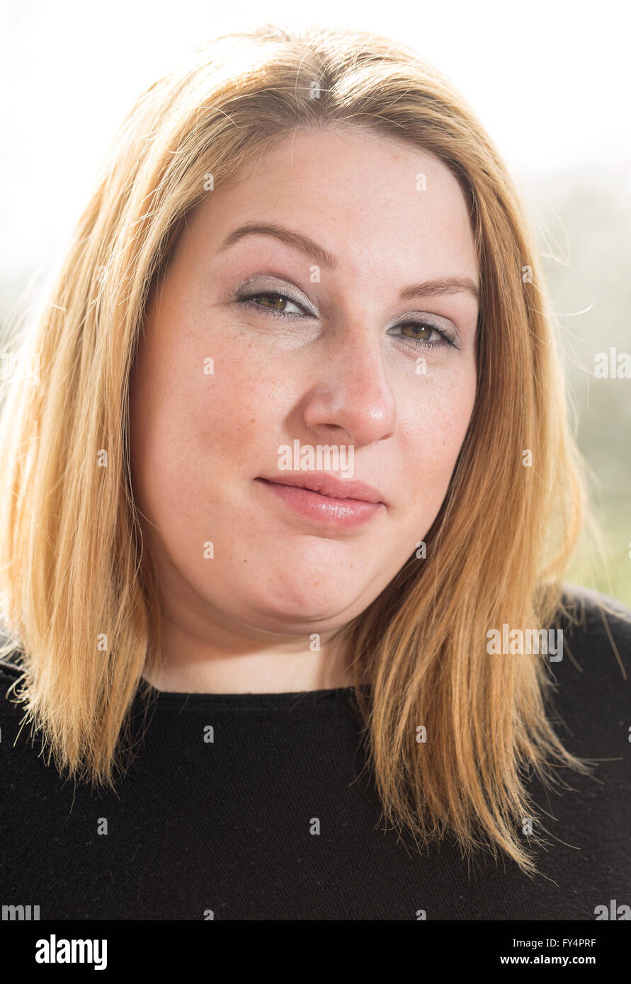 Klassische Kopfschuss. Eine junge Frau in einem schwarzen Top und kurzen blonden Haaren steht außen zurück, die von der Sonne beschienen. Sie sucht in der Stockfoto