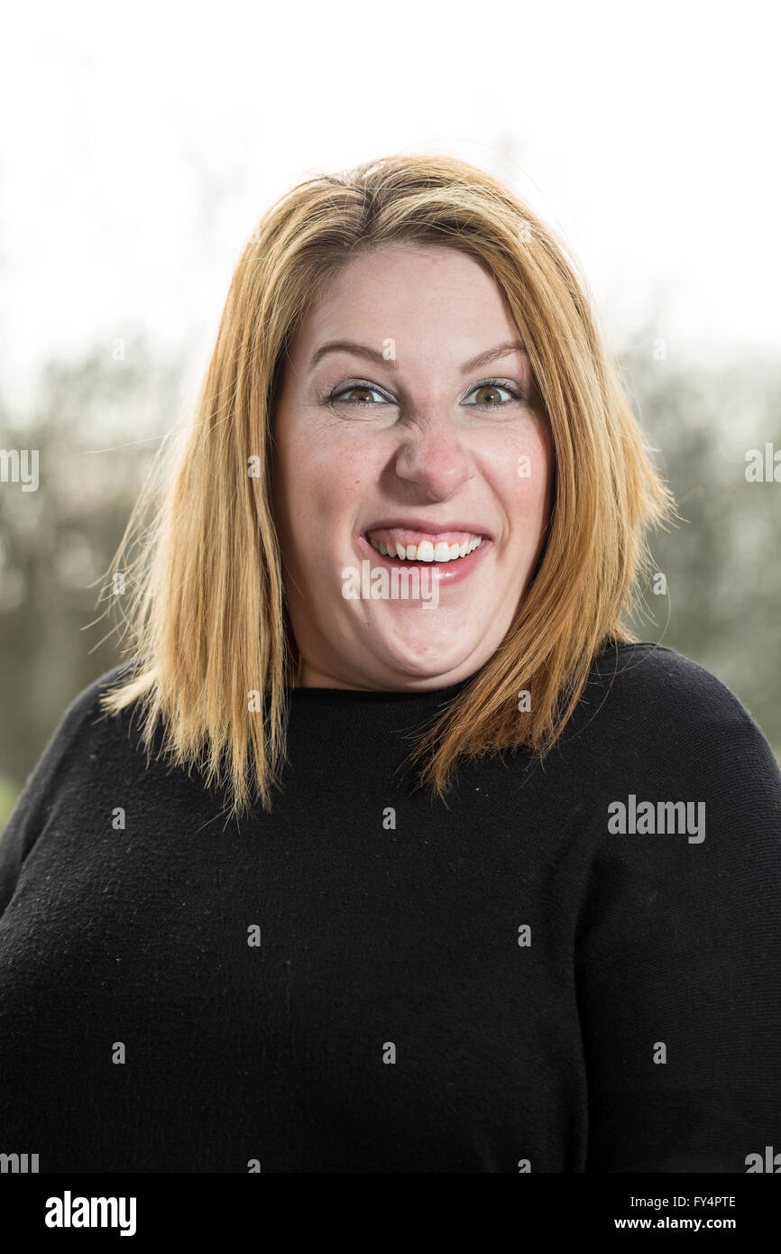 Klassische Kopfschuss. Eine junge Frau in einem schwarzen Top und kurzen blonden Haaren steht außen zurück, die von der Sonne beschienen. Sie sucht sehr amu Stockfoto