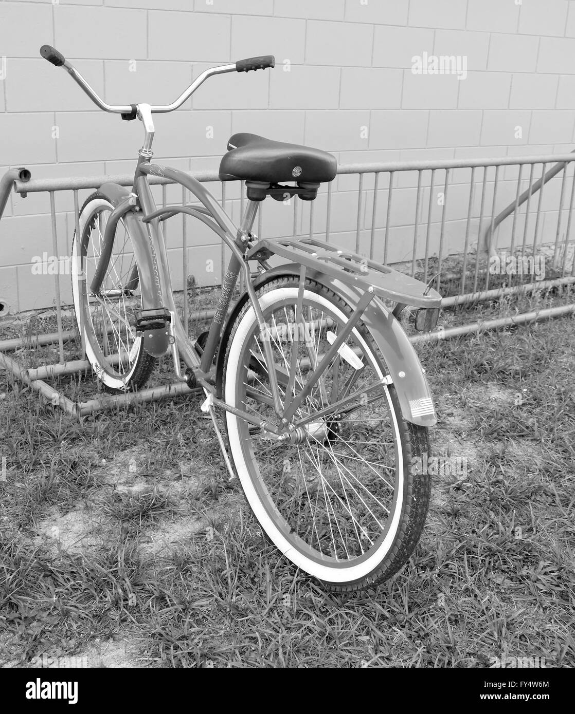 Alten Stil-Cruiser-Fahrrad in einem Rack gegen eine leere Wand, tatsächlich auf eine junior League Baseball Ground. April 2016 Stockfoto