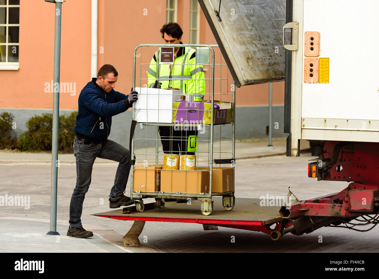 Trelleborg, Schweden - 12 April 2016: Zwei Männer werden mit einem Drahtgitter rolling Cart mit Ware von der Rückseite eines Staplers. Stockfoto