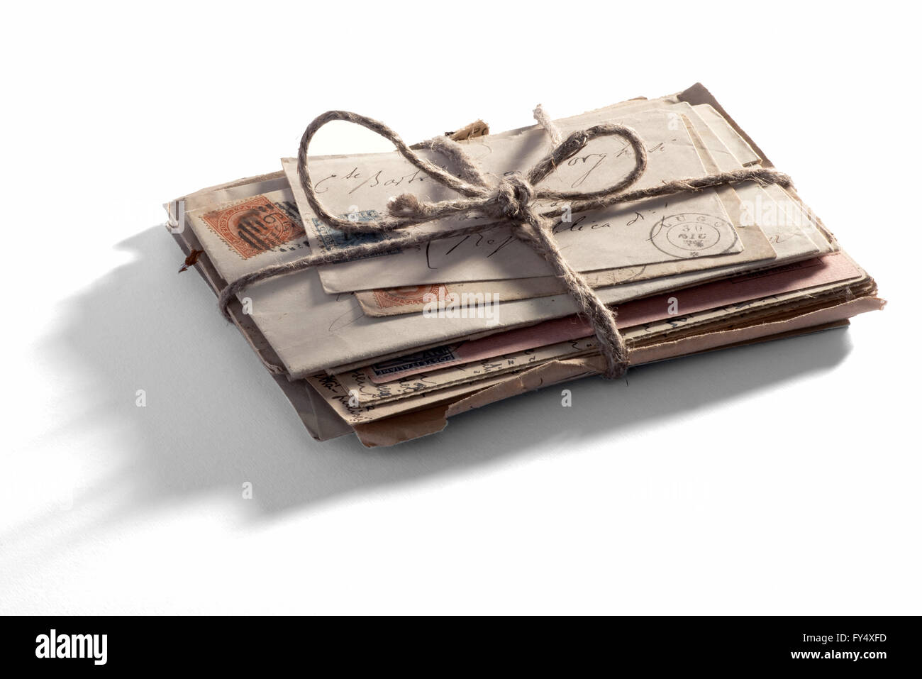 Haufen alte Vintage Briefe und Briefumschläge mit Poststempel gebunden mit Schnur an einen weißen Hintergrund mit Schatten Stockfoto