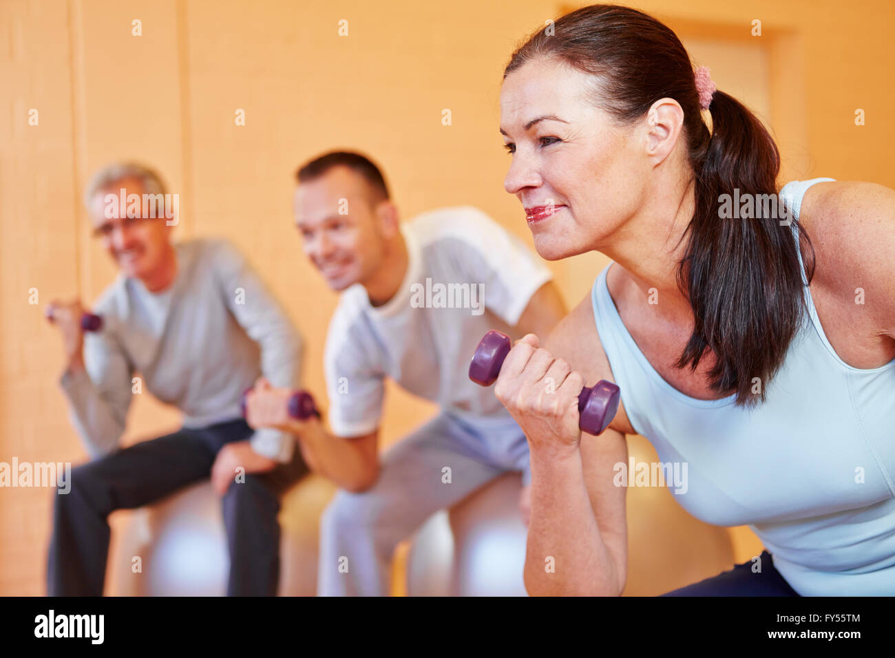 Ältere Frau lächelnd mit Hanteln im Rücken Kurs in einem Fitnesscenter Stockfoto