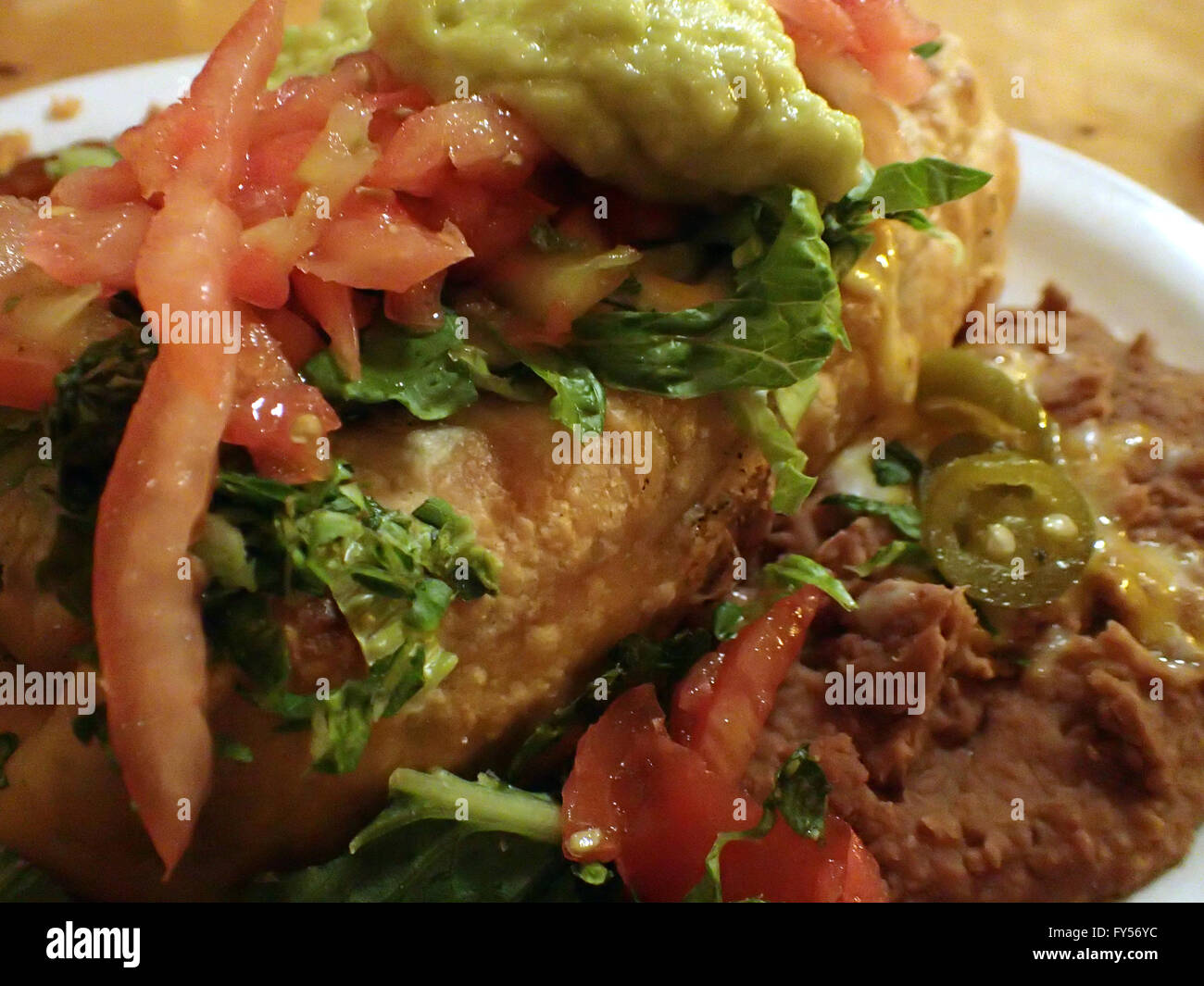 Nahaufnahme von Chimichanga garniert mit Salsa, Guacamole mit spanischen Reis, Bohnen, auf Tisch. Stockfoto