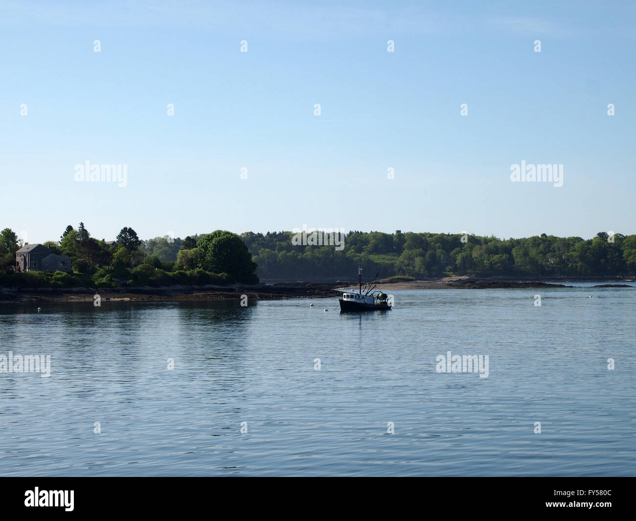 Angelboot/Fischerboot ruht in Wasser von Casco Bay vor der Küste der Insel mit Haus und Bäume in Maine. Stockfoto