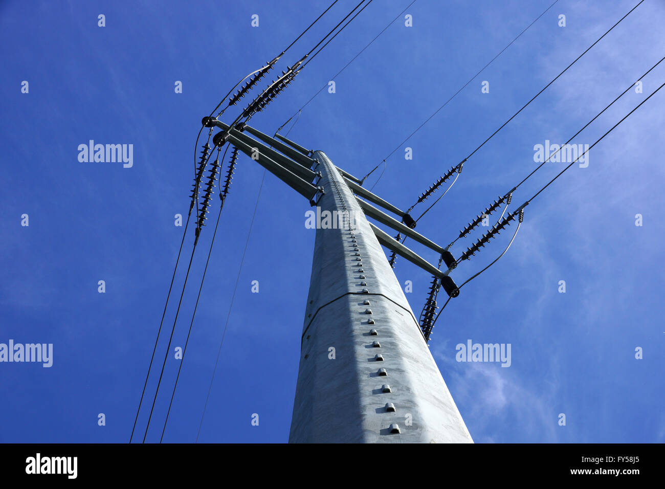 Hohen Hochspannungsleitungen schneiden sich an ein großes Metall Strommast in Maine vor blauem Himmel. Stockfoto