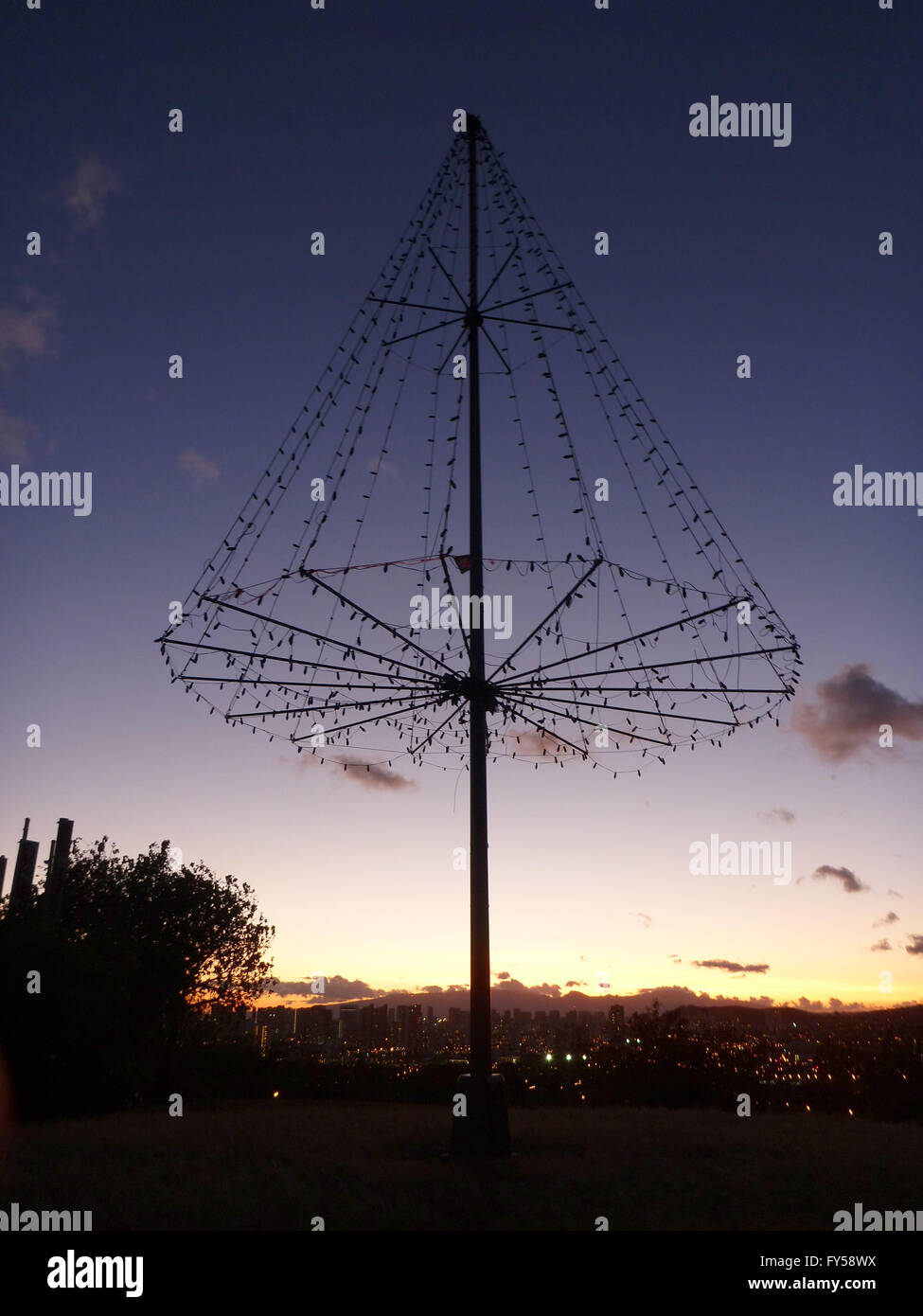 Kaimuki Weihnachtsbaum (Metall-Licht-Baum) am oberen Pu'u O Kaimuki (auch bekannt als Menehune Hill) in der Abenddämmerung auf mit Stadtbild von O Stockfoto