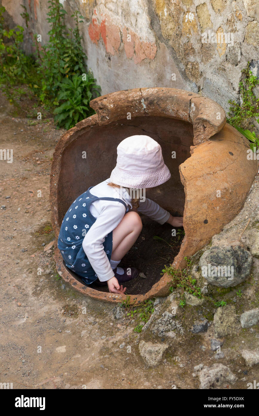 Junges Mädchen Tourist Touristen Kind Kinder Kind Kinder spielen und möglicherweise beschädigen Artefakte im Roman Herculaneum. In der Nähe von Neapel. Italien. Stockfoto