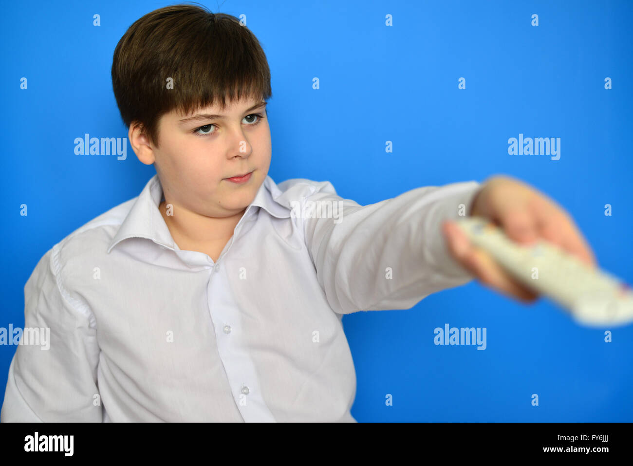 Junge Teenager mit TV-Fernbedienung auf blauem Hintergrund Stockfoto