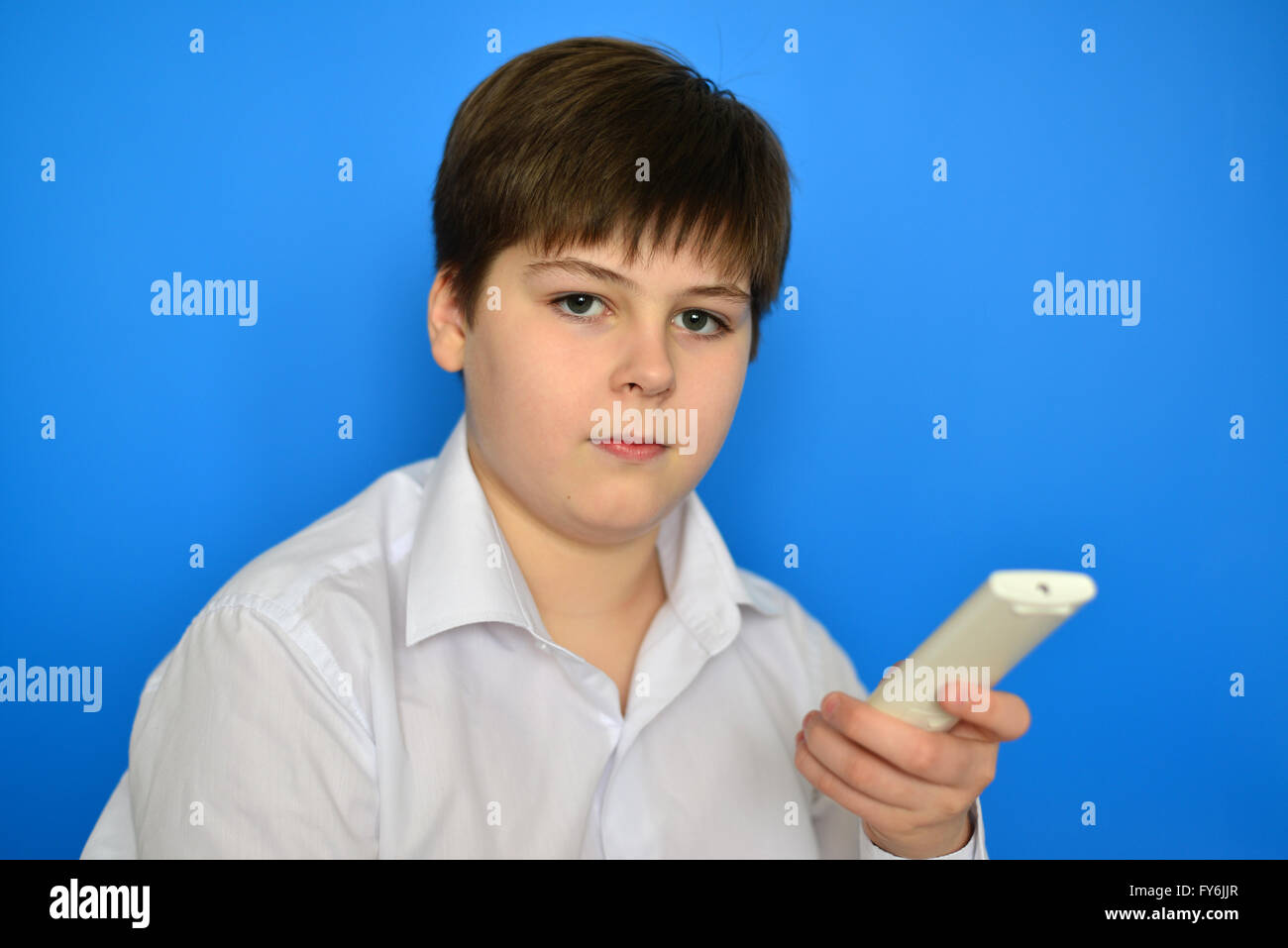 Junge Teenager mit TV-Fernbedienung auf blauem Hintergrund Stockfoto