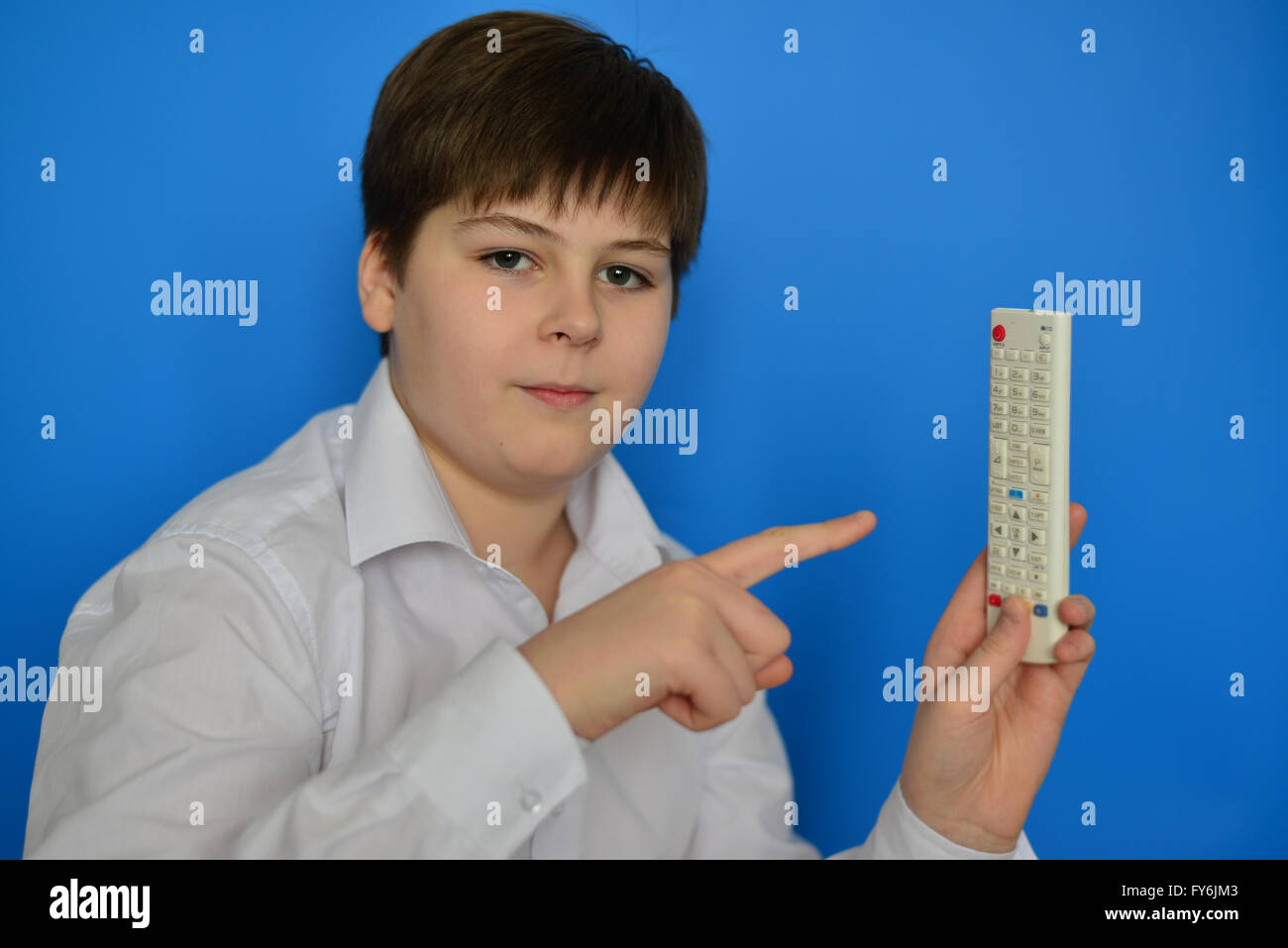 Junge Teenager mit TV-Fernbedienung auf blauem Hintergrund Stockfoto