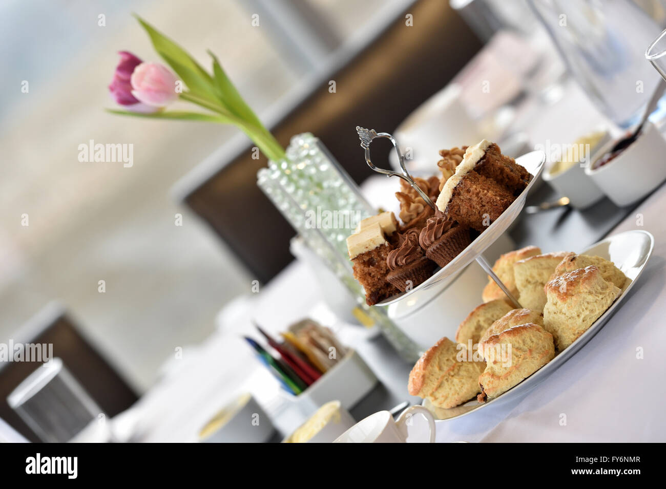 Tee in einem Unternehmensumfeld, Tulpen, Scones und Kuchen am Nachmittag Stockfoto