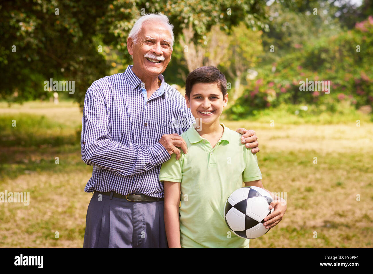 Opa mit Enkel: Porträt der ältere Mann mit seinem Enkel im Park Fußball zu spielen. Der alte Mann umarmt t Stockfoto