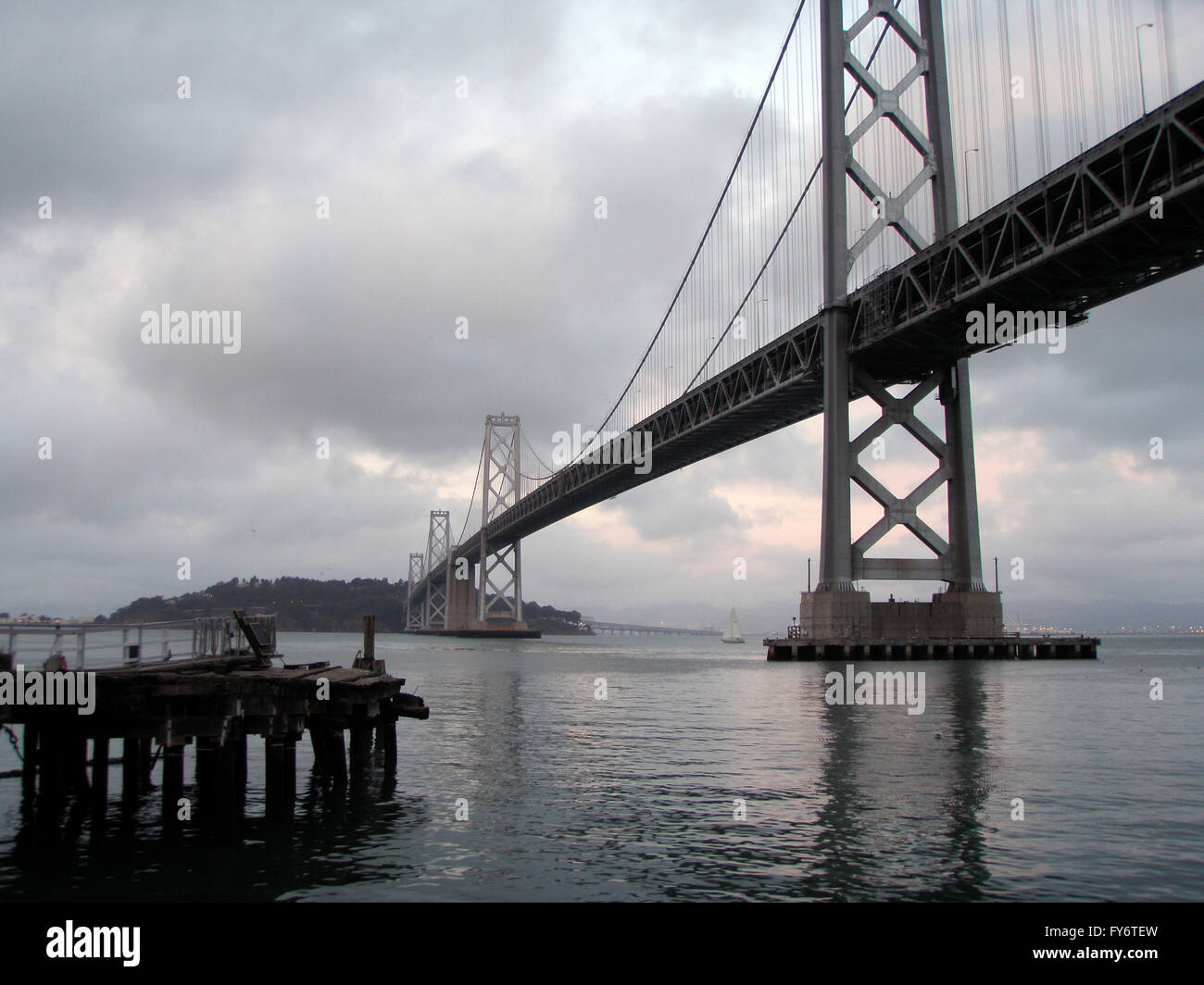 Alten Pier und Bay Bridge an einem nebeligen Tag mit einem Segel Boot im Hintergrund. Stockfoto