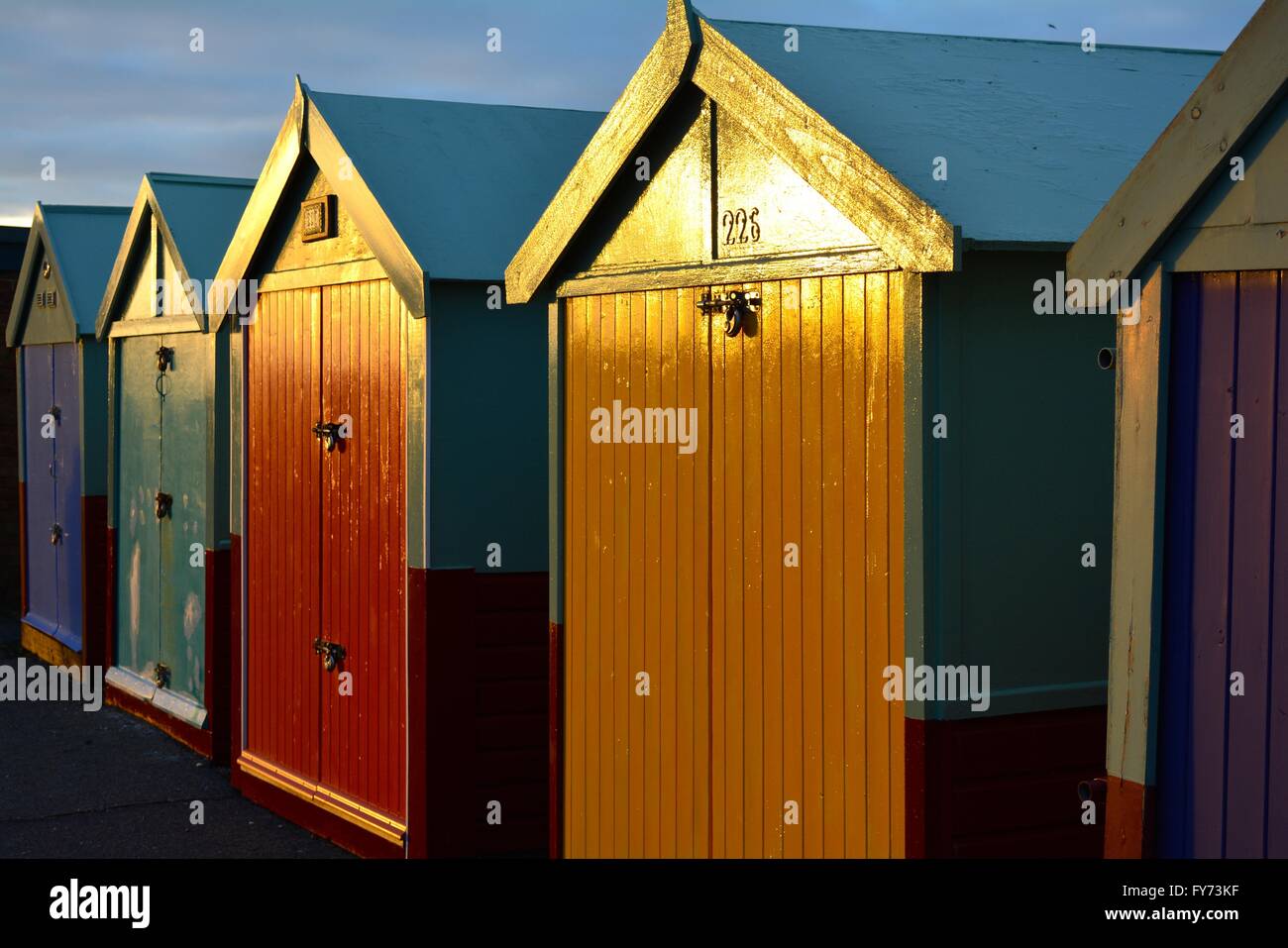 bunten Türen der Strandhütten auf Hove UK direkt am Meer bei Sonnenuntergang Stockfoto