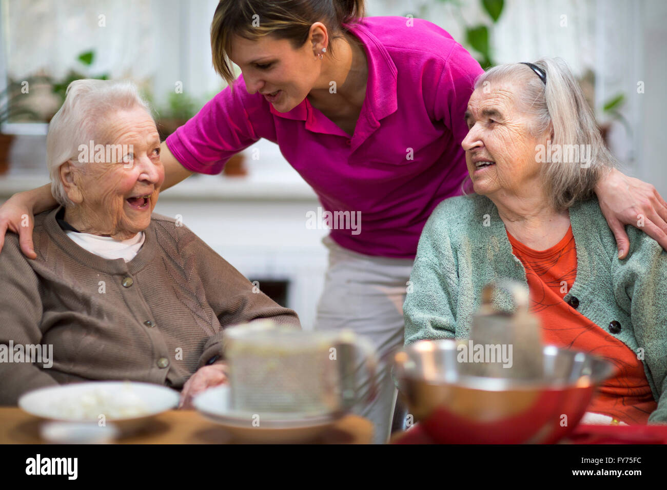 Zwei ältere Frauen, 78 Jahre und 88 Jahre und Betreuer für ältere Menschen, 31 Jahre, Freizeitaktivitäten in einem Pflegeheim Stockfoto