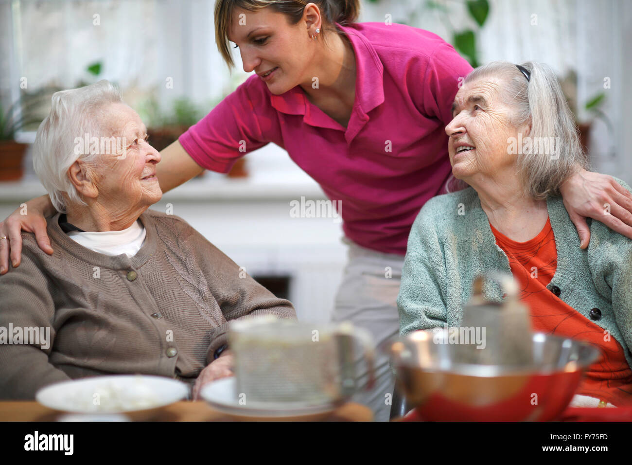Zwei ältere Frauen, 78 Jahre und 88 Jahre und Betreuer für ältere Menschen, 31 Jahre, Freizeitaktivitäten in einem Pflegeheim Stockfoto