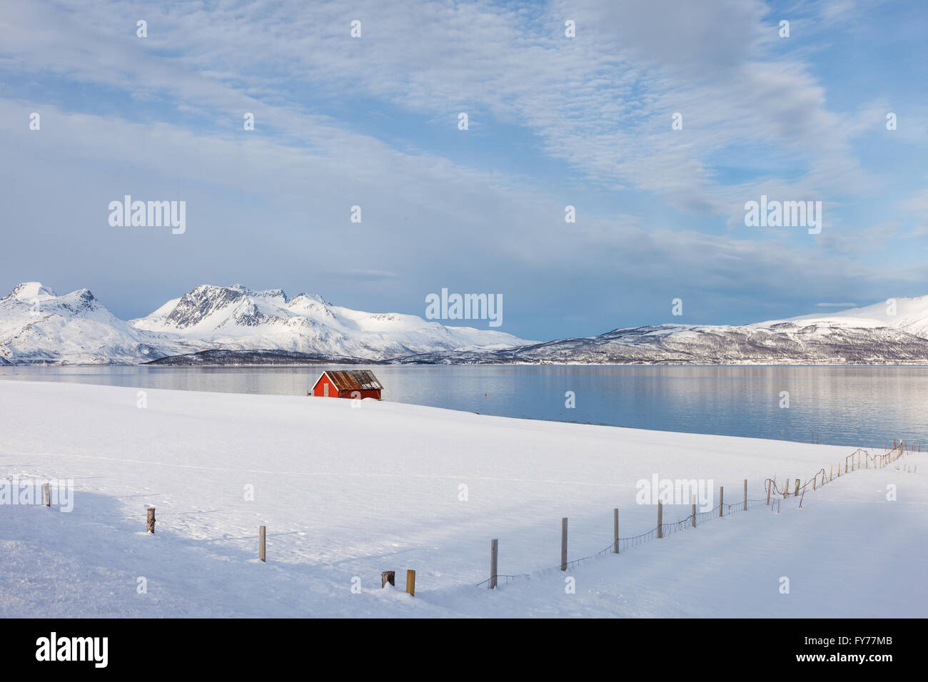 Schneeberge und rote Kabine von einem Fjord im arktischen Norwegen Stockfoto