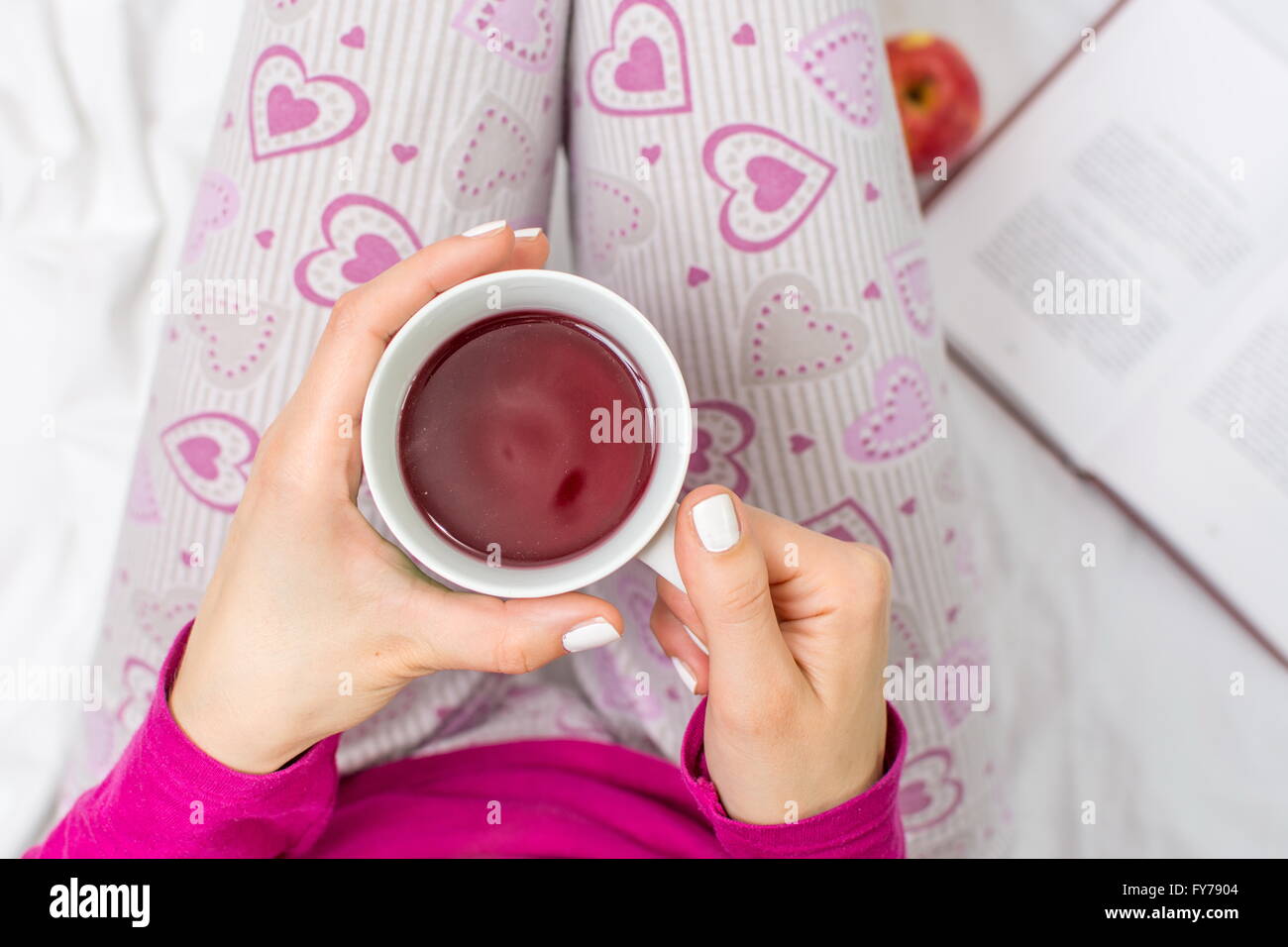 Frau mit einer Tasse Früchtetee im Bett Stockfoto