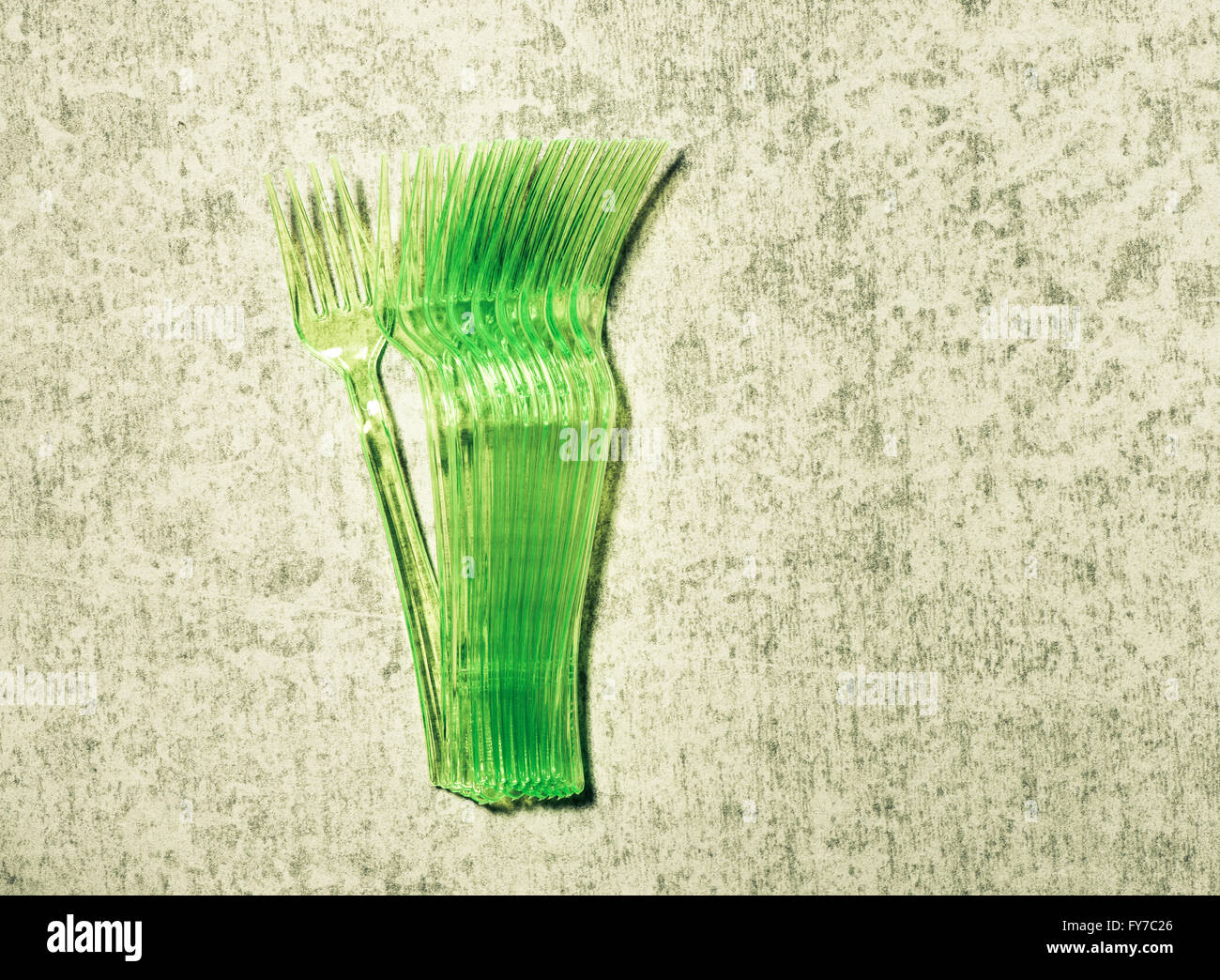Grüne Kunststoff-Gabeln auf steinernen Tisch liegend Stockfoto