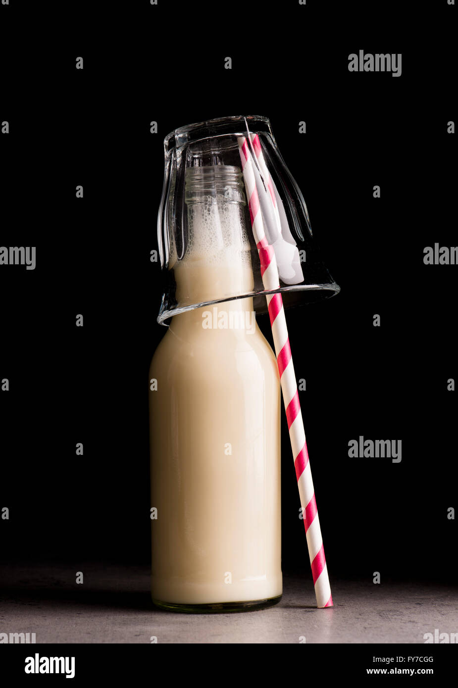Soja-Milch in Glasflasche und gestreiften Trinkhalm. Schwarzer Hintergrund. Stockfoto
