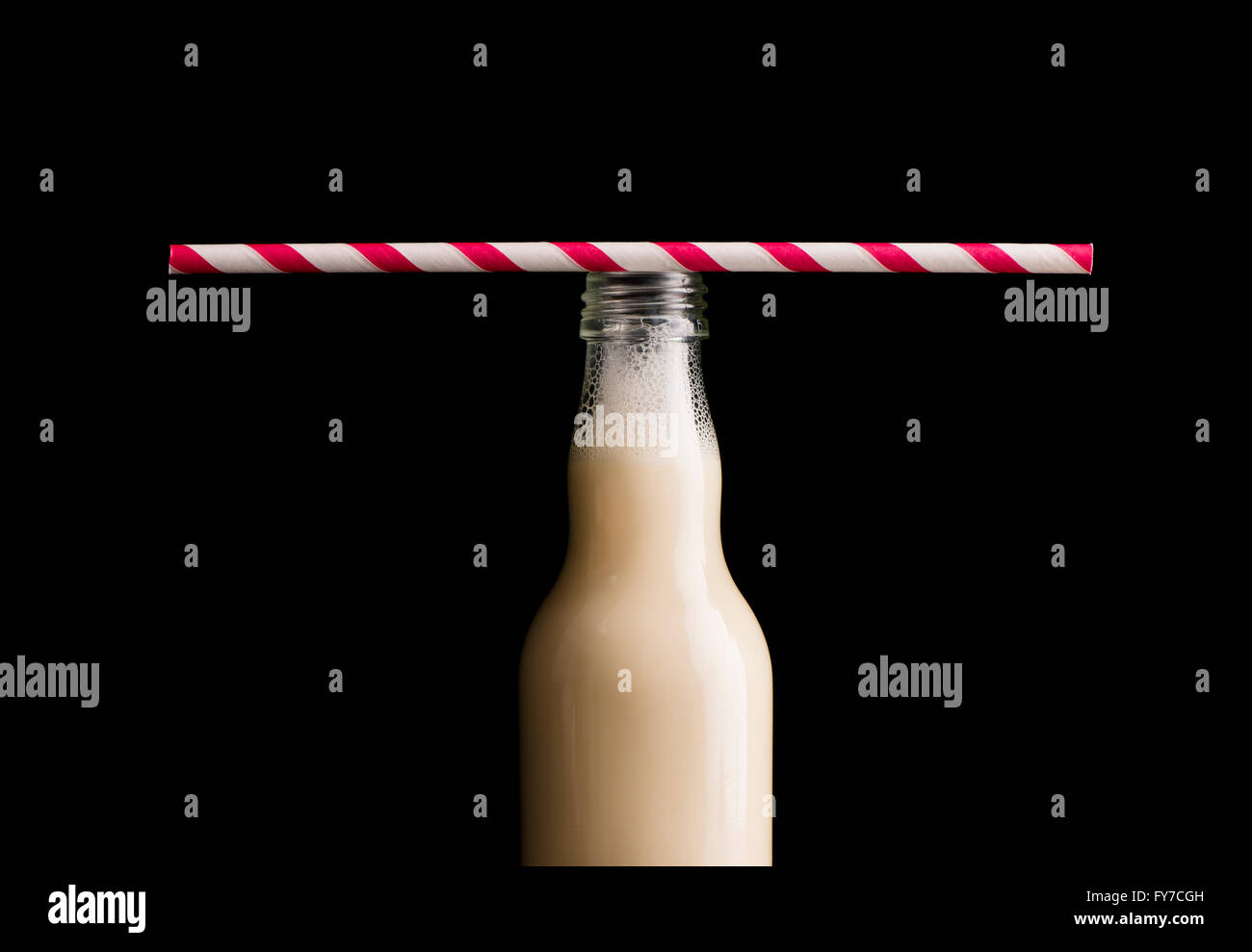 Soja-Milch in Glasflasche und gestreiften Trinkhalm. Schwarzer Hintergrund. Stockfoto