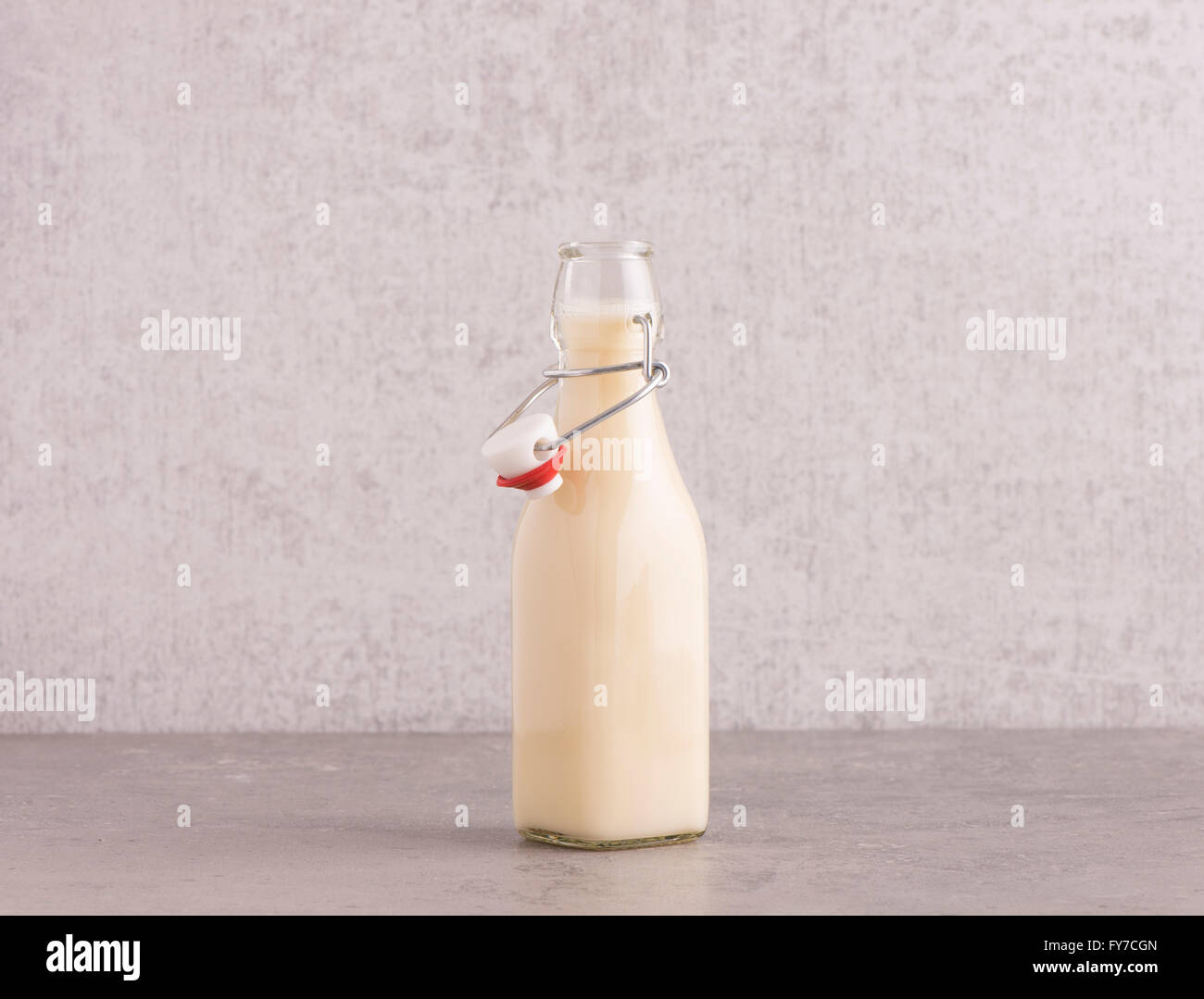 Hafermilch in einer Glasflasche am Küchentisch. Hintergrund mit textfreiraum Steinmauer. Stockfoto