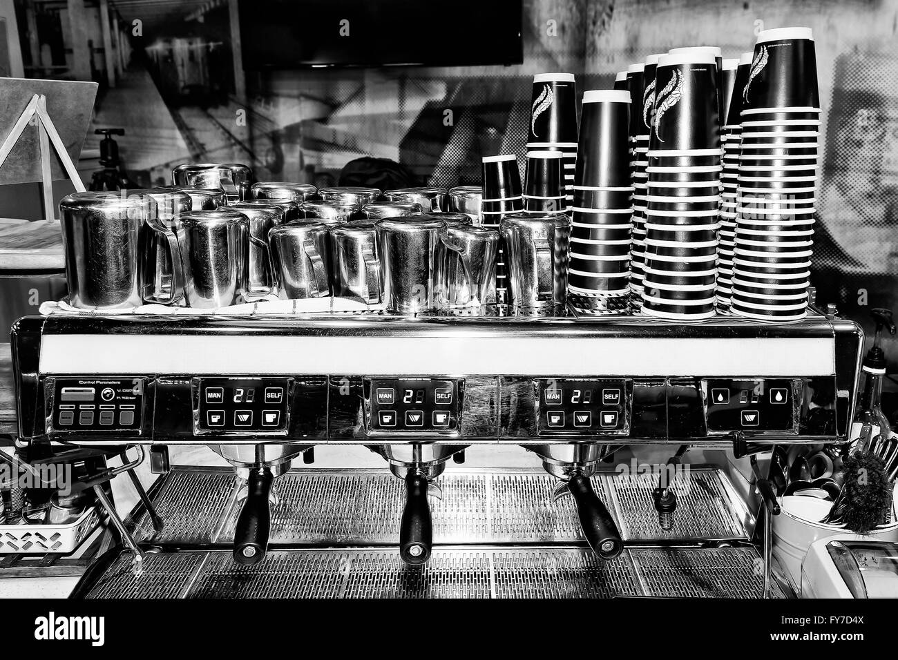 Schwarz weißes Bild der großen industriellen Barista Kaffee Maschine in einem Café Kunden mit Haufen von Tassen und Mil servierfertig Stockfoto