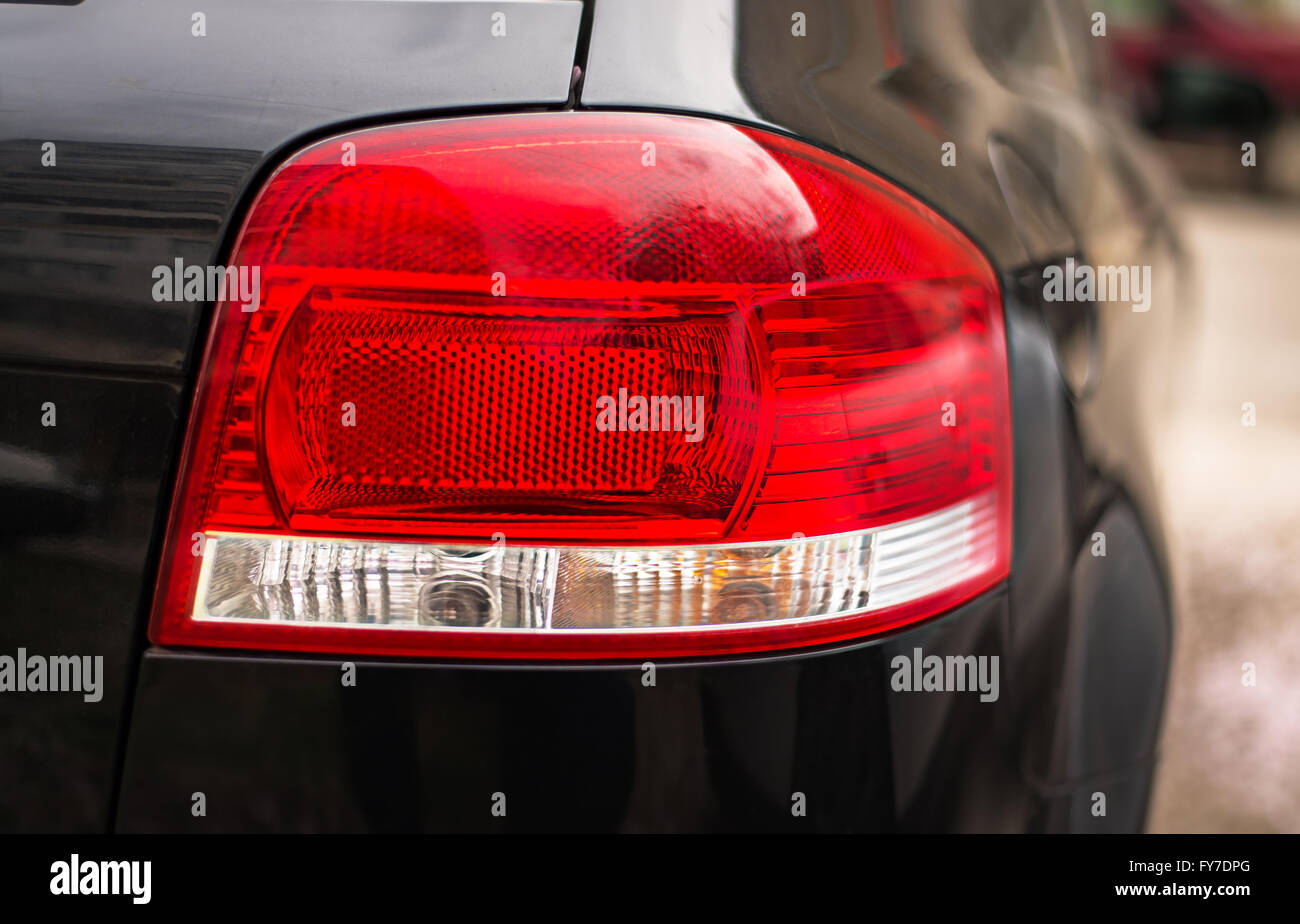 Nahaufnahme von einem Rücklicht auf ein modernes schwarzes Auto mit Reflexion. Stockfoto