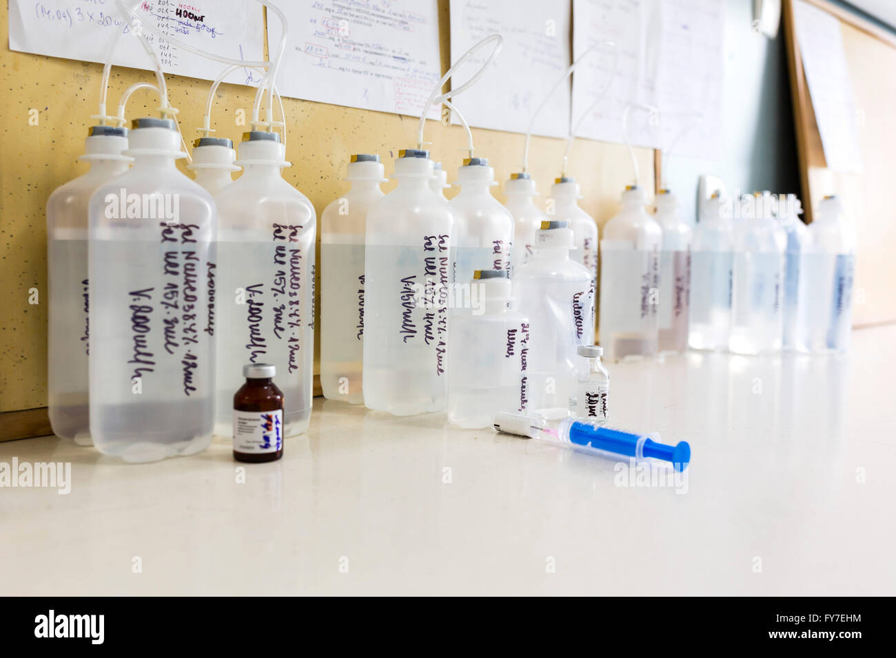 Verschiedene Tanks von Kochsalzlösung in einer Krankenhaus-Tabelle. Blaue Nadel neben ihnen. Stockfoto