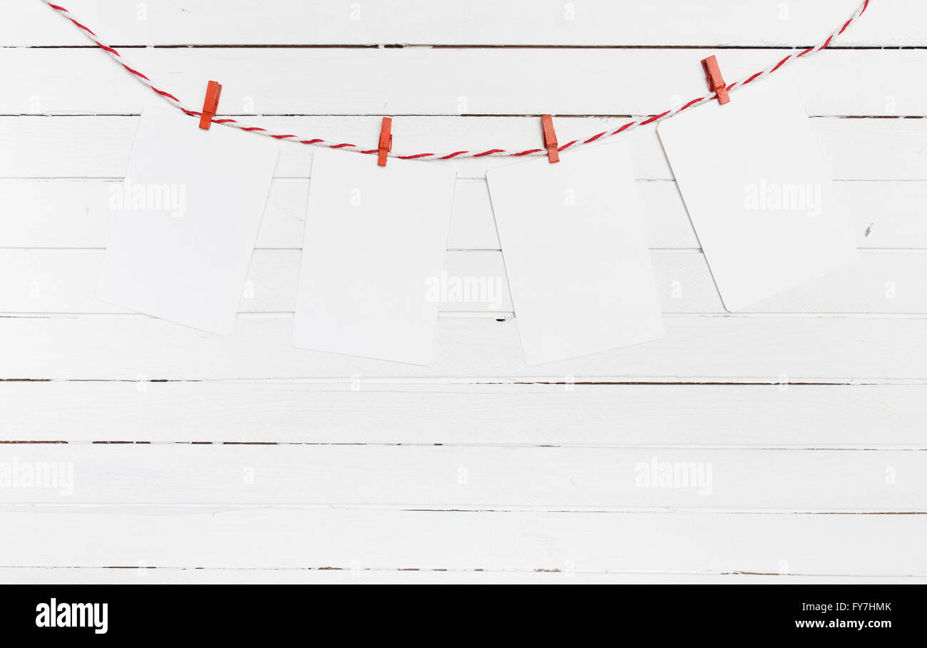 Leeres Papier oder Foto Rahmen rot gestreiften Wäscheleine hängen. Auf hölzernen Hintergrund. Vorlage für Ihren Text. Stockfoto