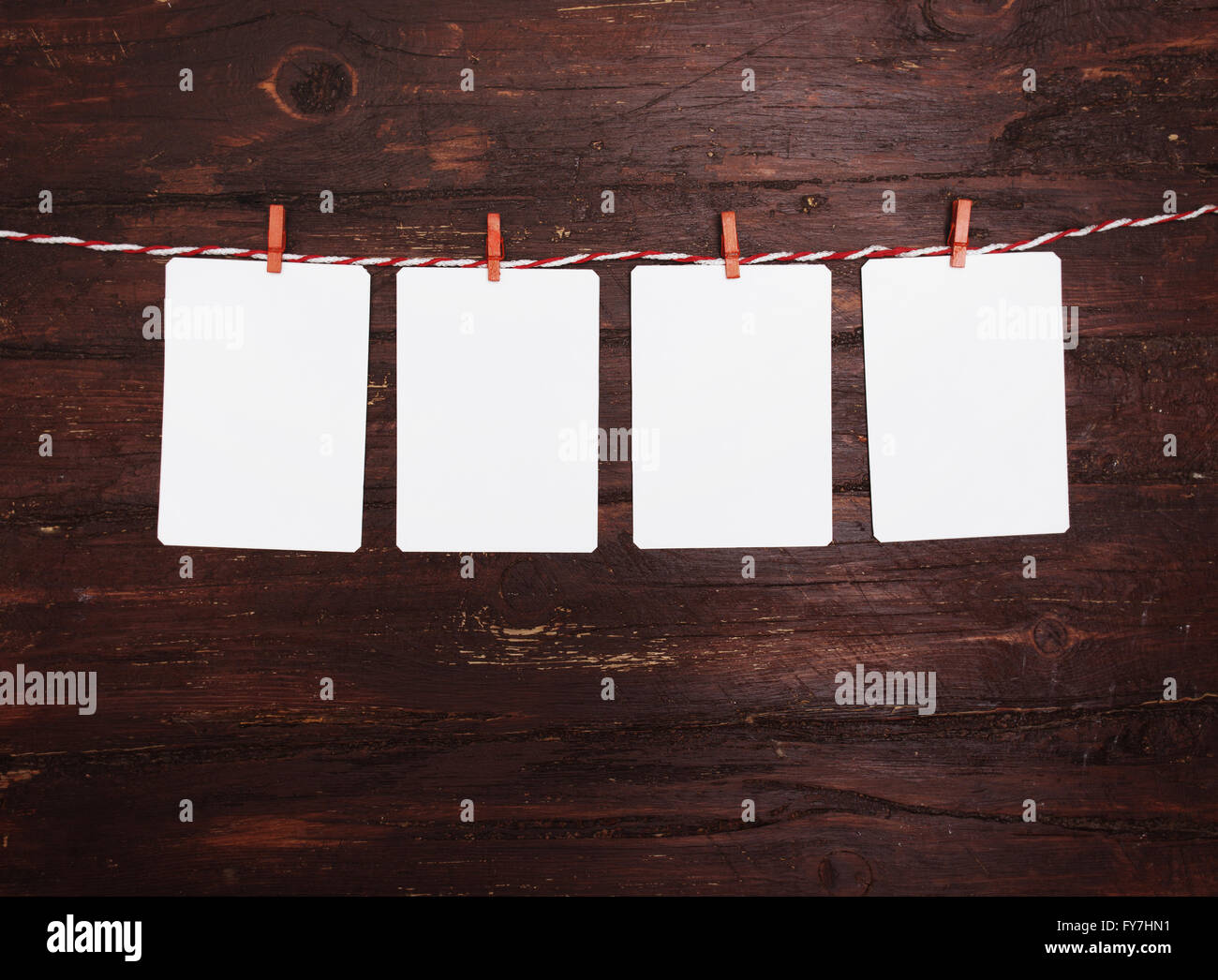 Leeres Papier oder Foto Rahmen rot gestreiften Wäscheleine hängen. Auf hölzernen Hintergrund. Vorlage für Ihren Text. Stockfoto