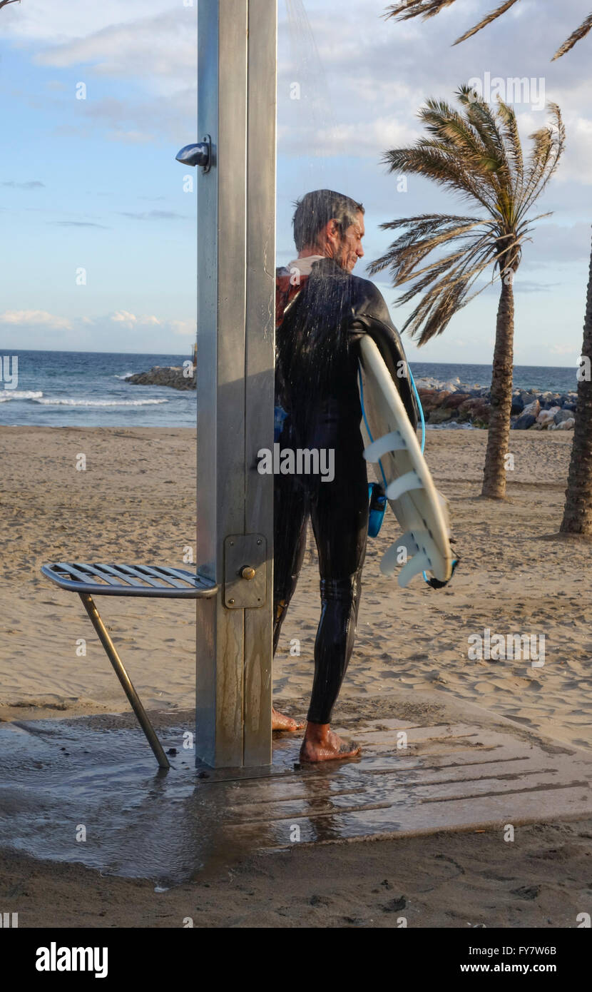 Surfer im Neoprenanzug mit Surfbrett unter der Dusche am Strand am Mittelmeer, Andalusien, Spanien. Stockfoto