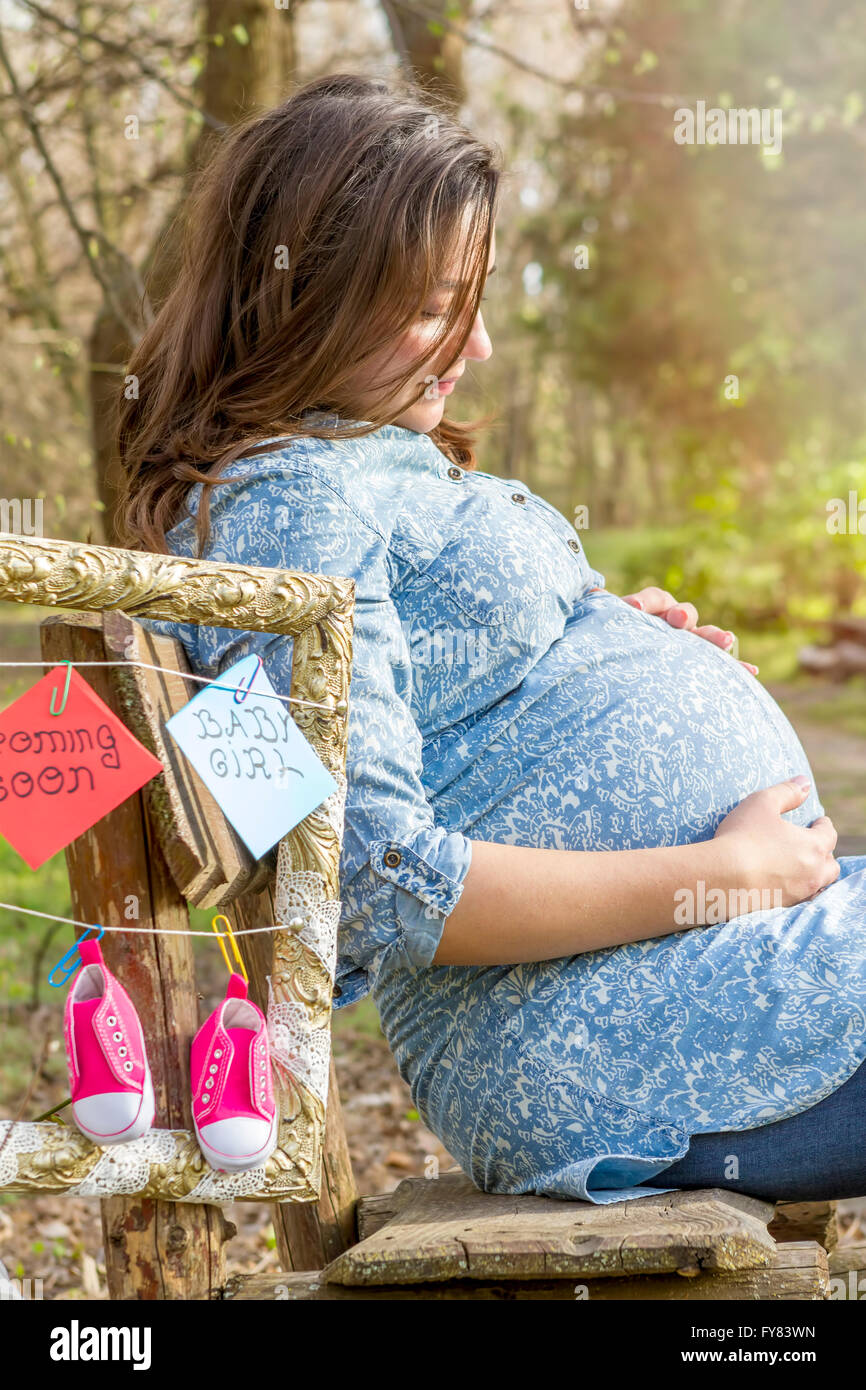 Schöne schwangere Frau outdoor im Park auf der Bank zu denken. Stockfoto