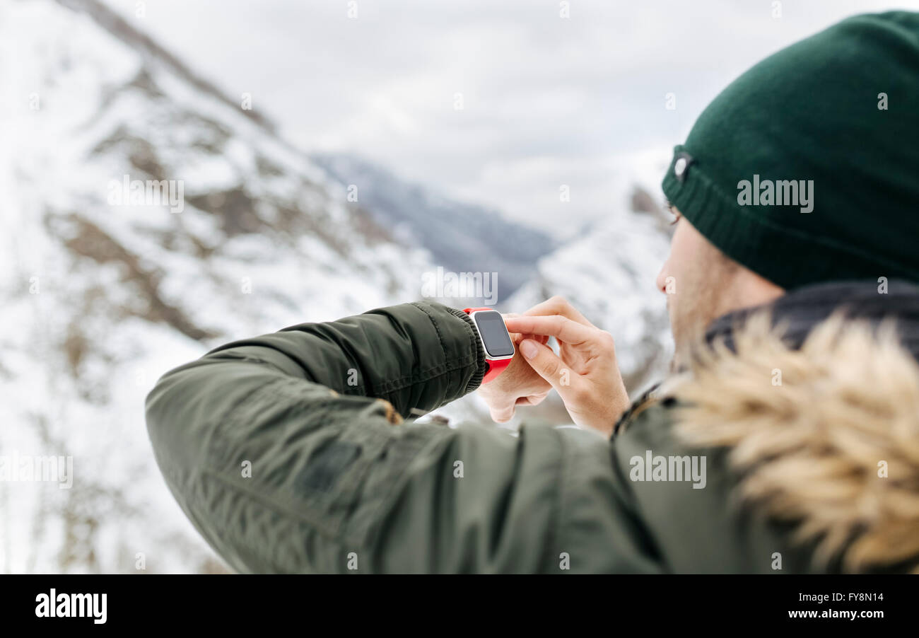 Spanien, Asturien, junger Mann mit Smartwatch in den verschneiten Bergen Stockfoto