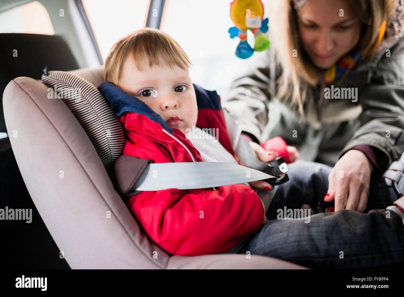 Frau, Befestigung Sitz Glocke seines kleinen Sohnes im Kindersitz im Auto sitzen Stockfoto