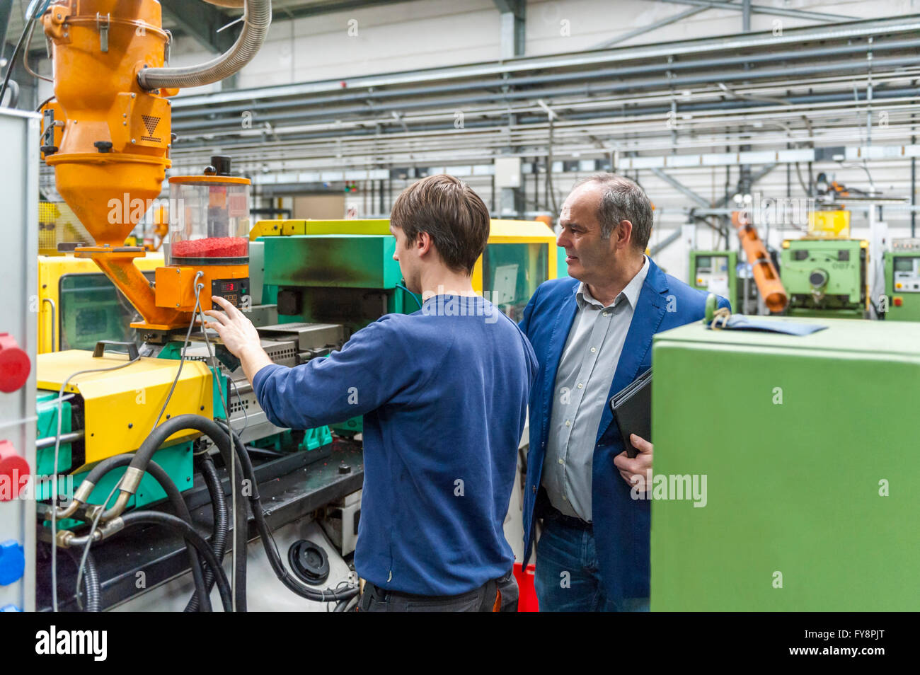 Zwei Personen in Kunststoff Fabrik Maschinen anpassen Stockfoto