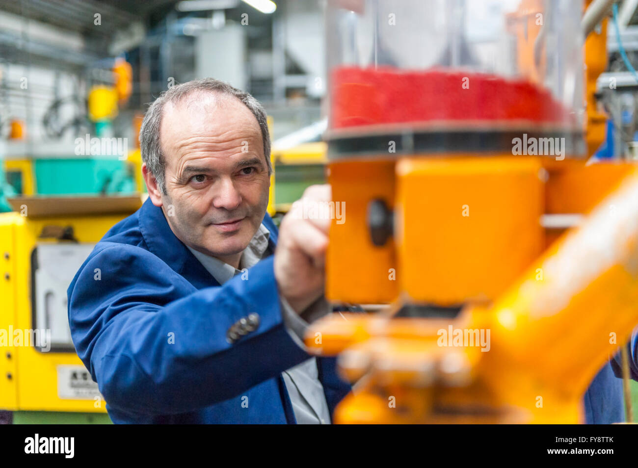 Mann in Kunststoff Fabrik Anpassung Produktionsmaschine Stockfoto