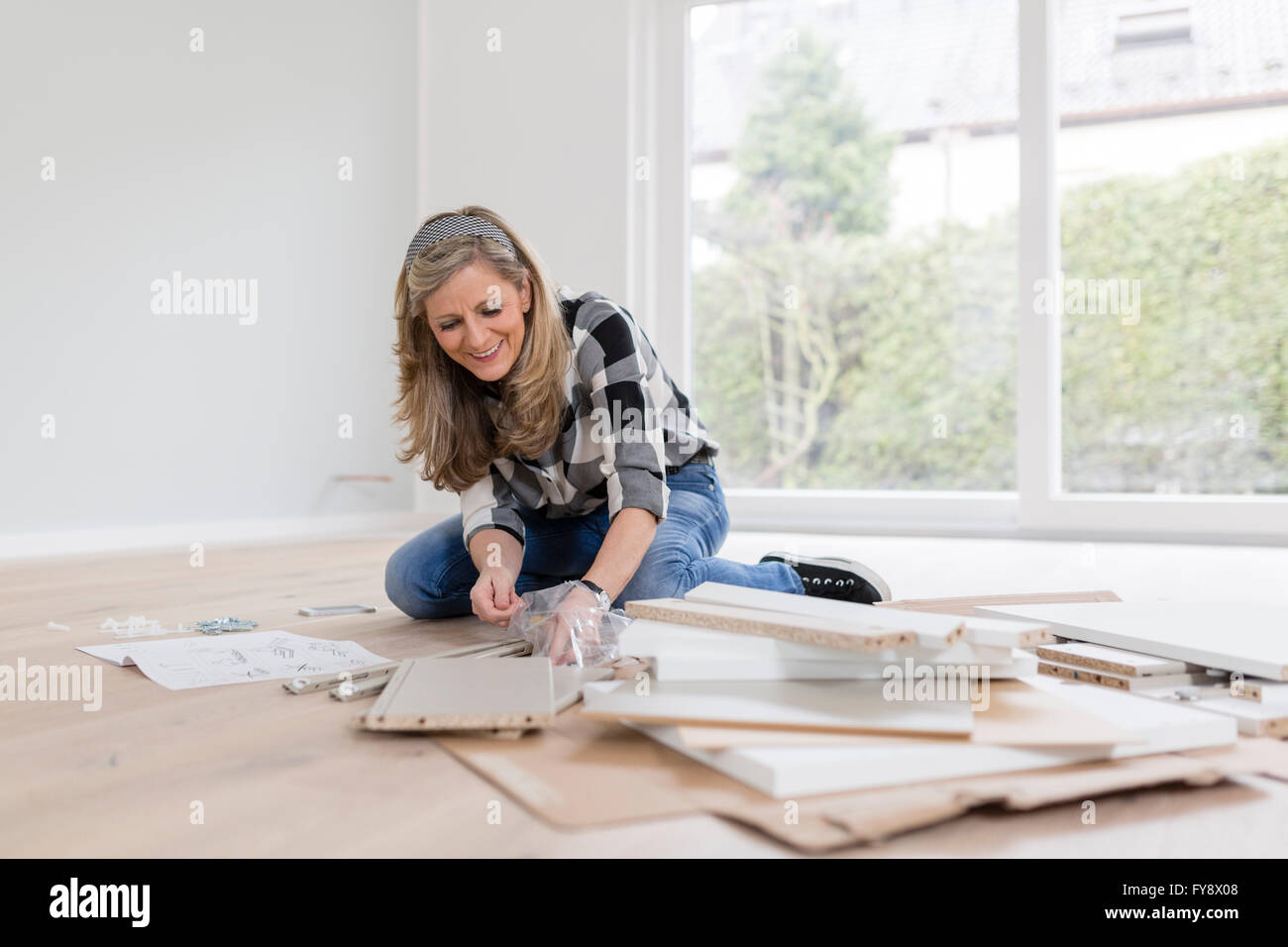 Frau hocken auf dem Boden Auspacken Bestandteile eines Kabinetts Stockfoto