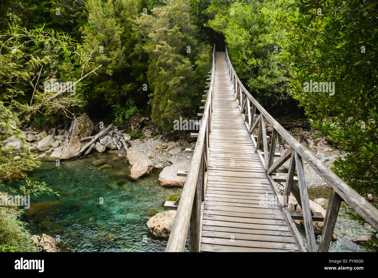 Hölzerne Brücke über einem klaren, blauen Fluss, Parque Pumalín, Patagonien, Chile Stockfoto