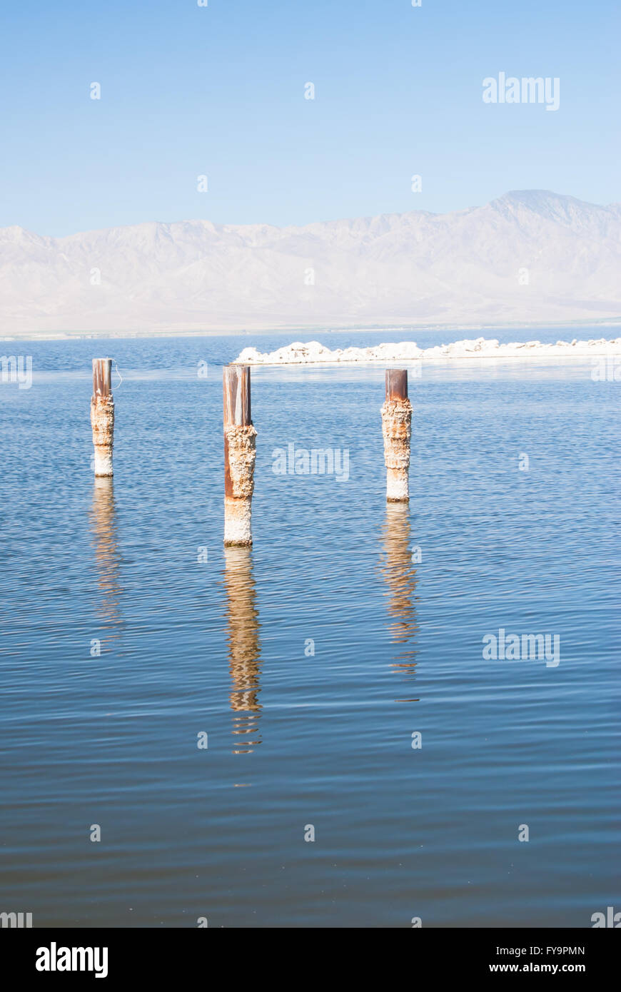 Beiträge spiegeln sich im Wasser an einem trüben Sommertag am Salton Sea Kalifornien Stockfoto