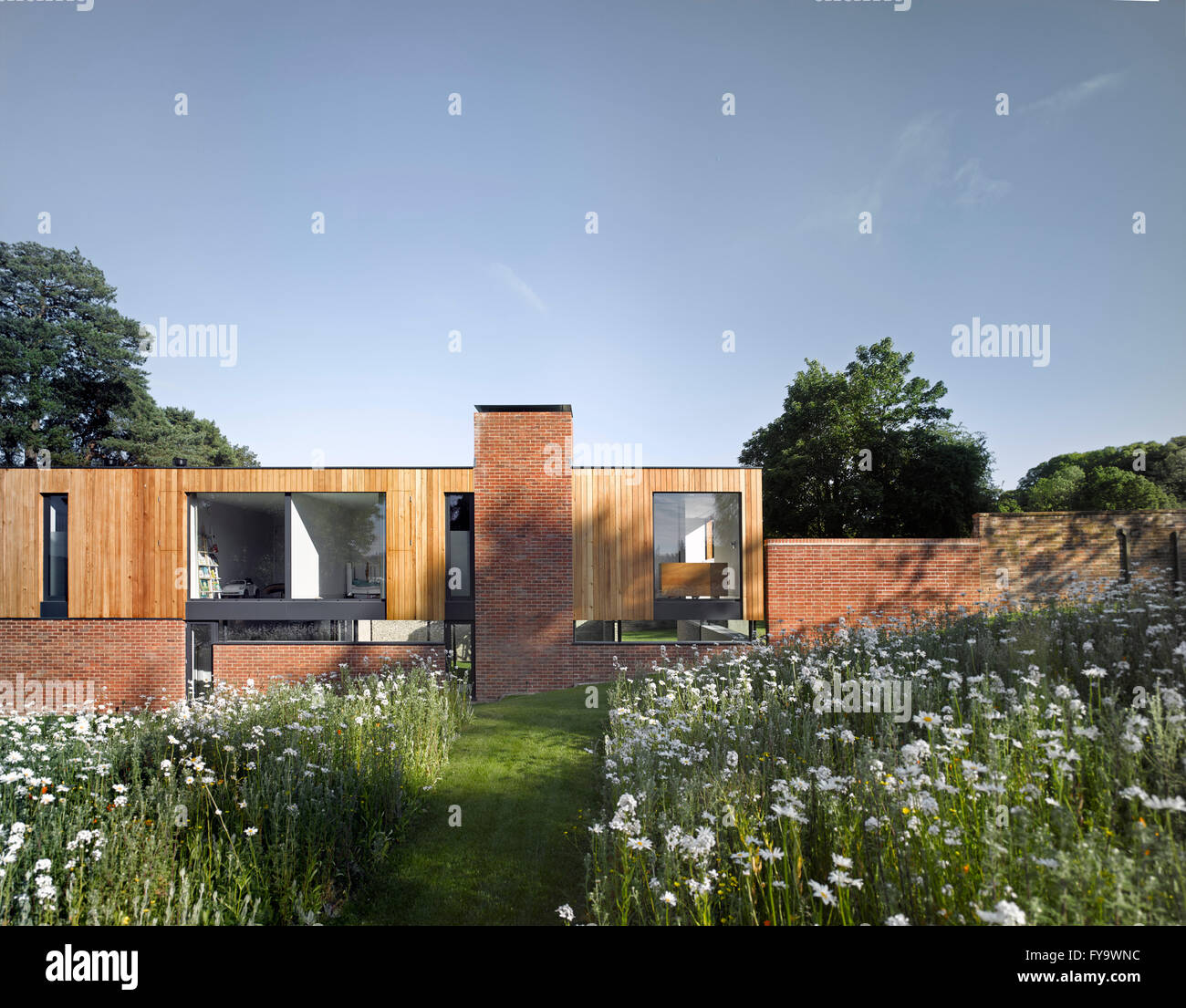 Ein modernistisches Haus auf einem historischen ummauerten Garten mit einer Wildblumenwiese gesetzt. Cheeran Haus, Lower Basildon, Großbritannien. Architekt: John Pardey Architekten, 2015. Stockfoto