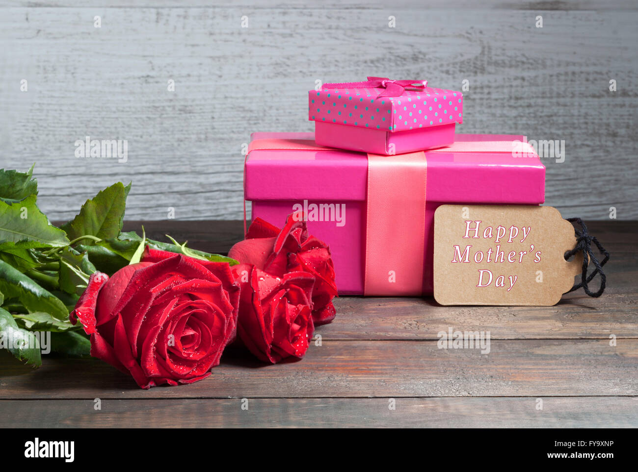 Glücklich Muttertag Text mit roten Rosen und Rosa Geschenk-Boxen auf Holztisch Stockfoto