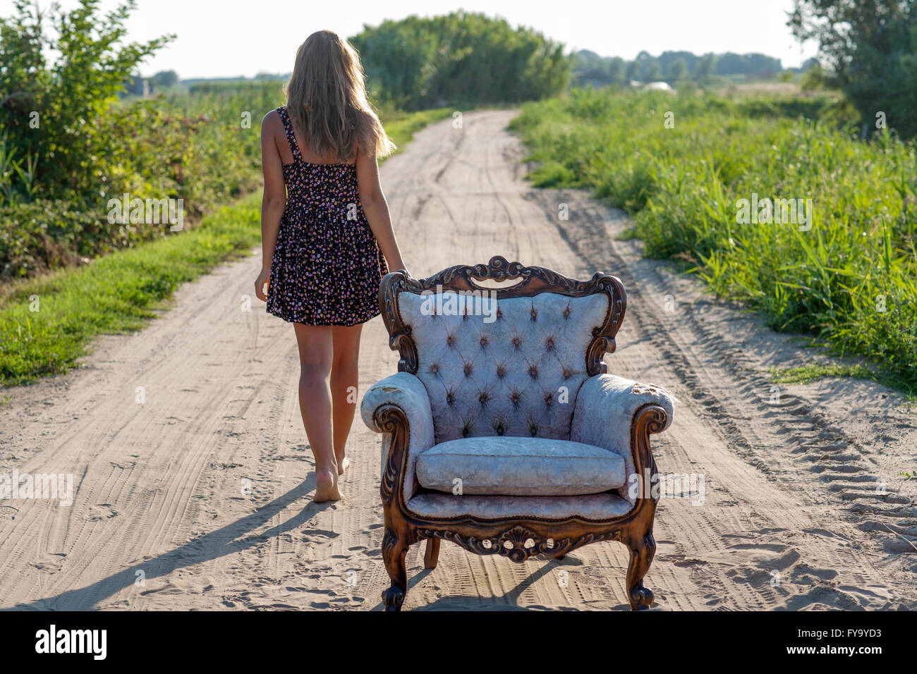 Mädchen, 14 Jahre, zu Fuß entlang einer Strecke, einen alten Sessel vor Stockfoto