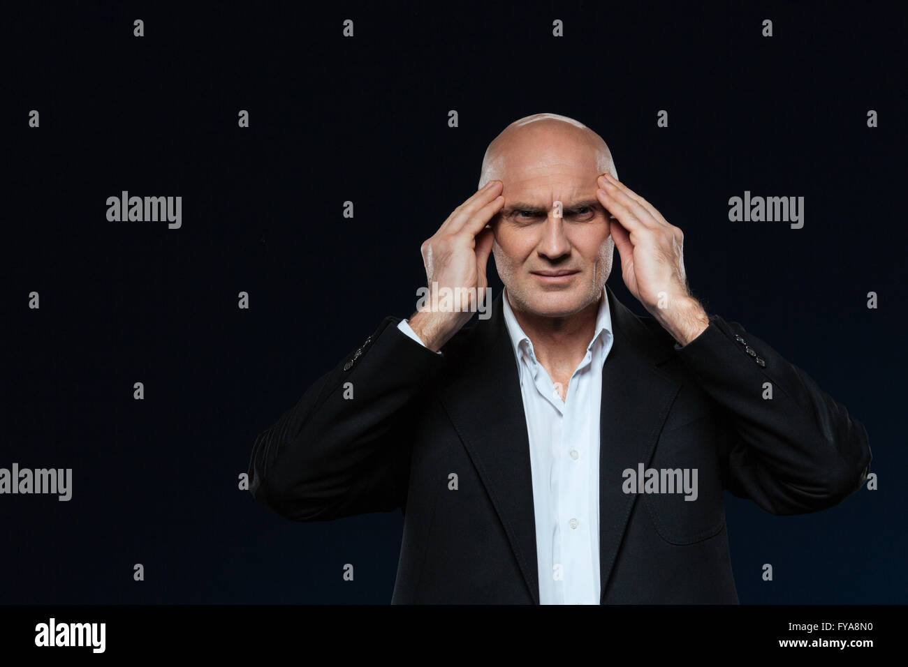 Reife Geschäftsmann mit Kopfschmerzen stehen auf schwarzem Hintergrund Stockfoto