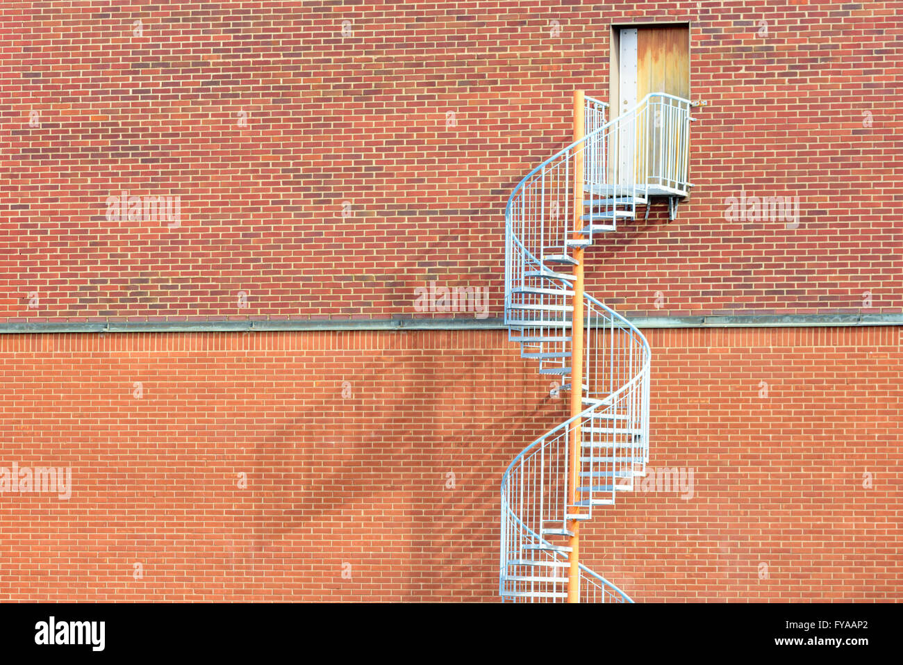 Spiralförmig Metall-Treppe, oben eine rote Mauer eine Tür ohne Griff. Dies ist einen Notausgang, nicht aus eingegeben werden sollen die Stockfoto Spiralförmig Metall-Treppe, oben eine rote Mauer eine Tür ohne Griff. Dies ist einen Notausgang, nicht aus eingegeben werden sollen die Stockfoto