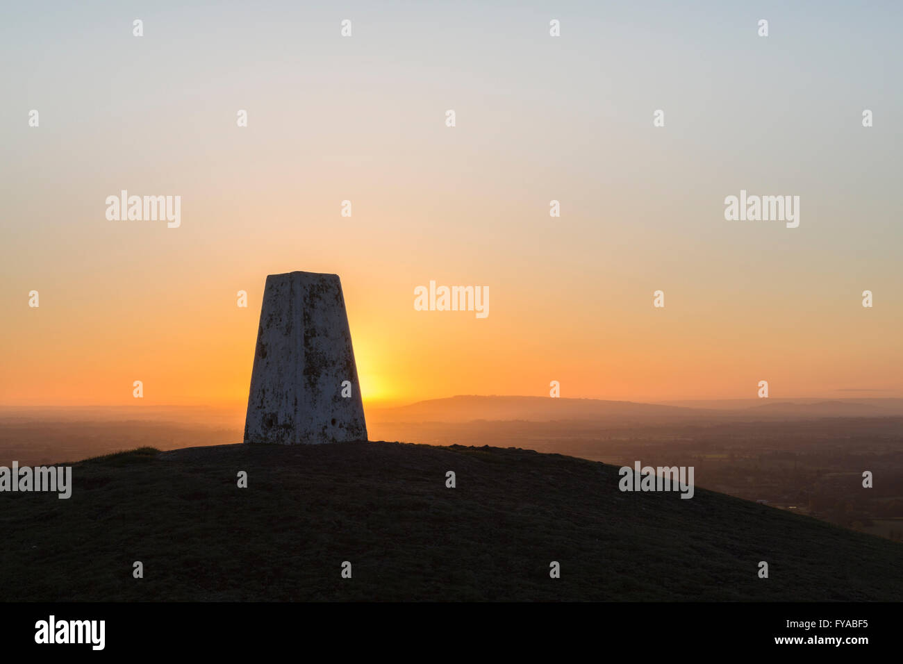 Die Sonne geht hinter einer Triangulation Station oder Trig Punkt an einem klaren Morgen. Stockfoto
