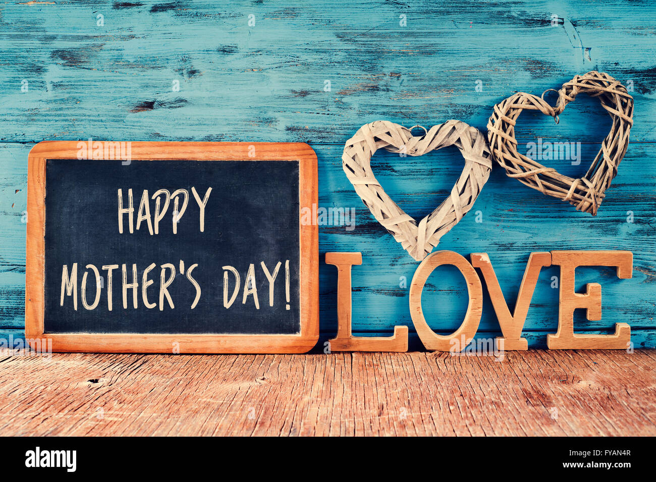 der Text happy Muttertag in einer Tafel geschrieben neben einigen Holzbuchstaben bilden das Wort Liebe und einige rustikale Hand platziert Stockfoto