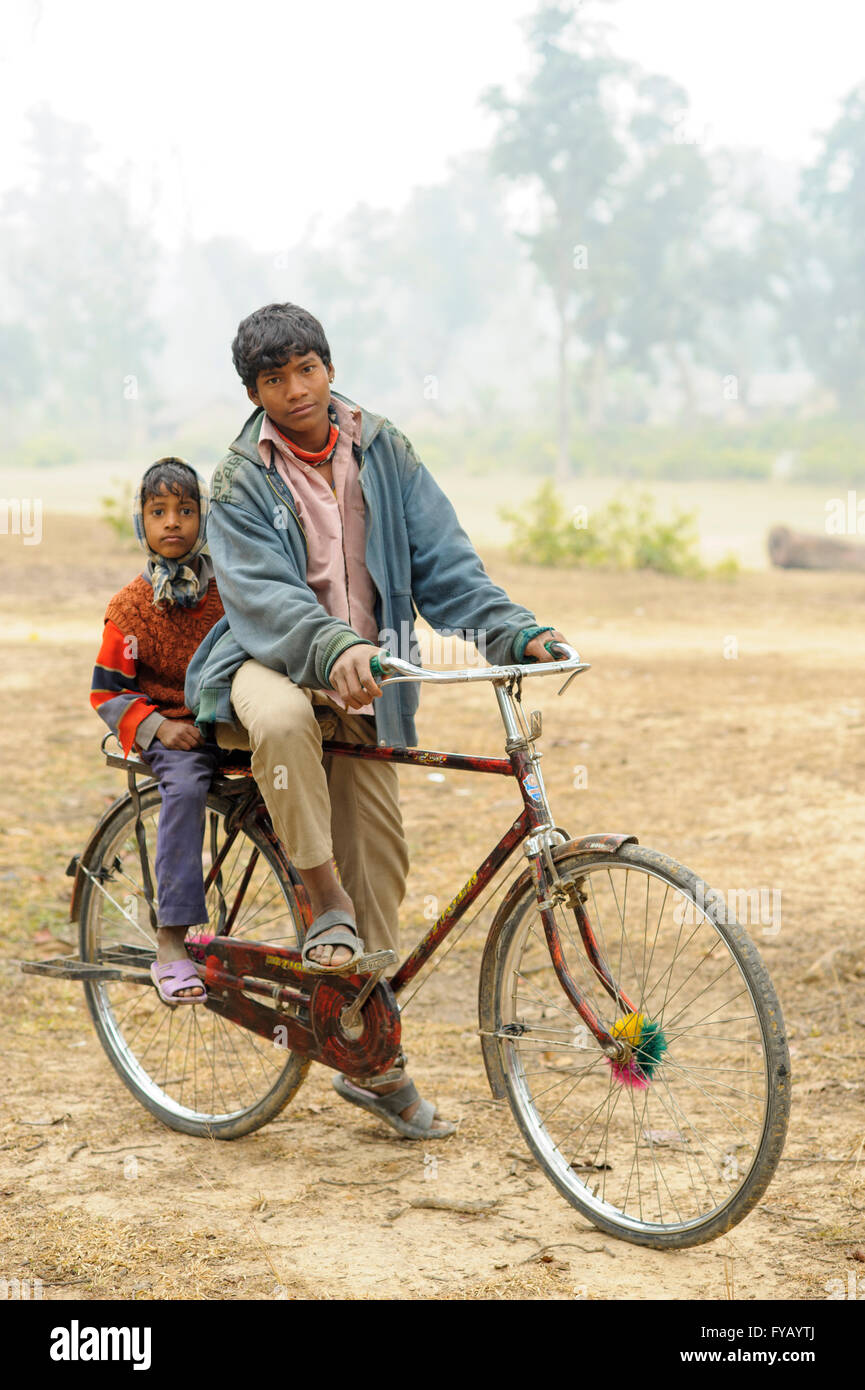 Jüngeren Knaben Fahrten Sozius mit großen Bruder durch Trockenwald in Nepal Stockfoto
