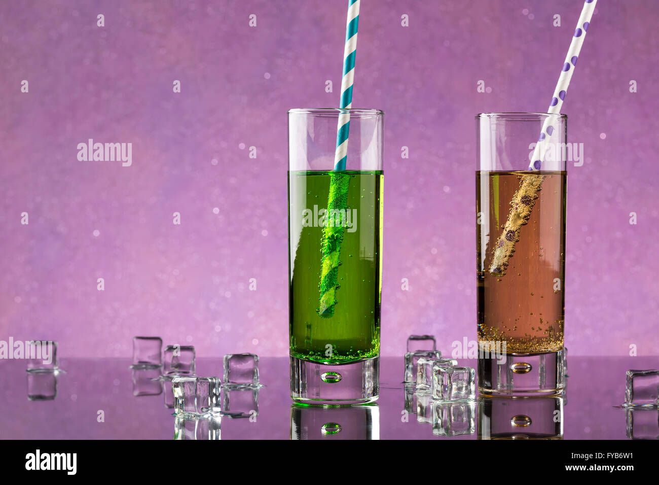 Set von zwei Collins Glas mit Soda und bunte Strohhalme. Geschmolzene Eiswürfel dekoriert. Stockfoto