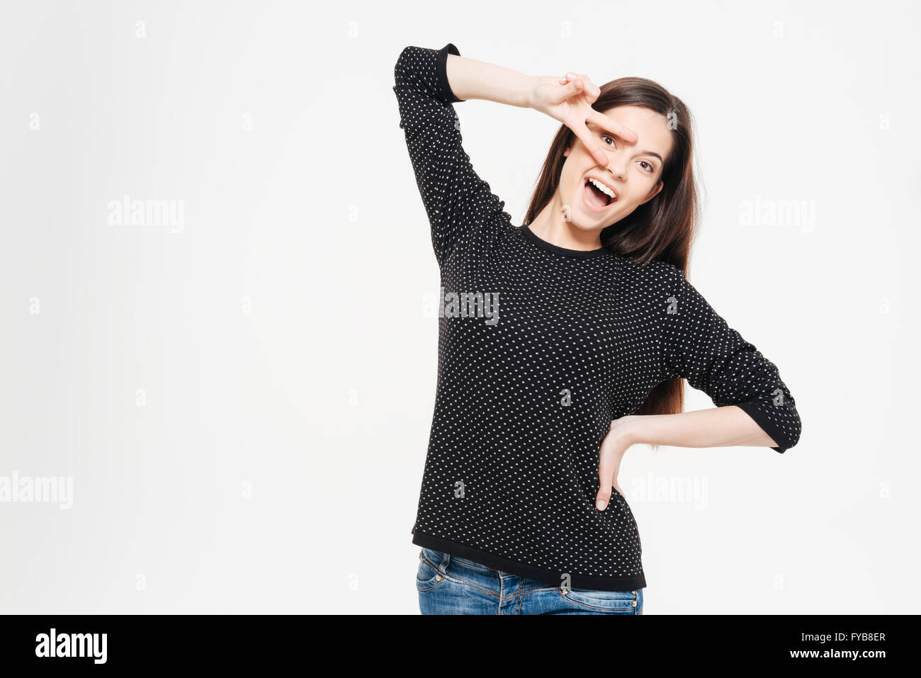 Fröhliche Frau, die mit Peace-Zeichen auf einem weißen Hintergrund isoliert Stockfoto